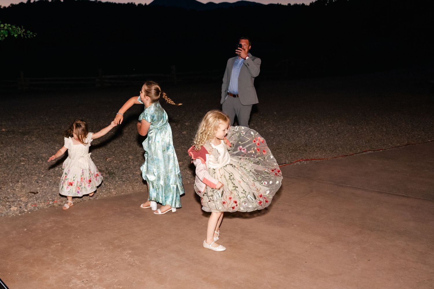 Guests dancing and celebrating at a nighttime outdoor party with string lights overhead.