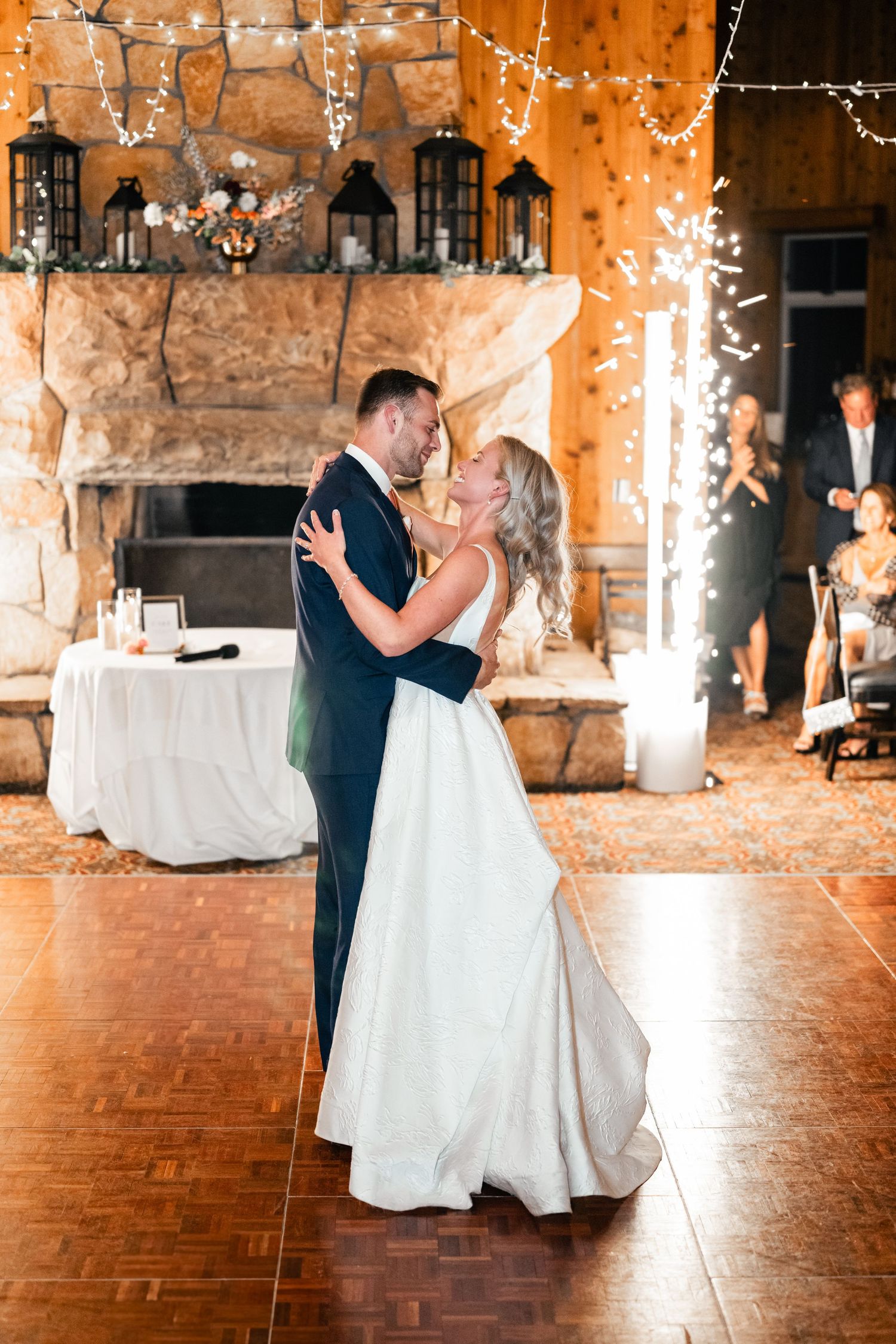 Wedding couple sharing their first dance in a rustic stone venue decorated with twinkling string lights.