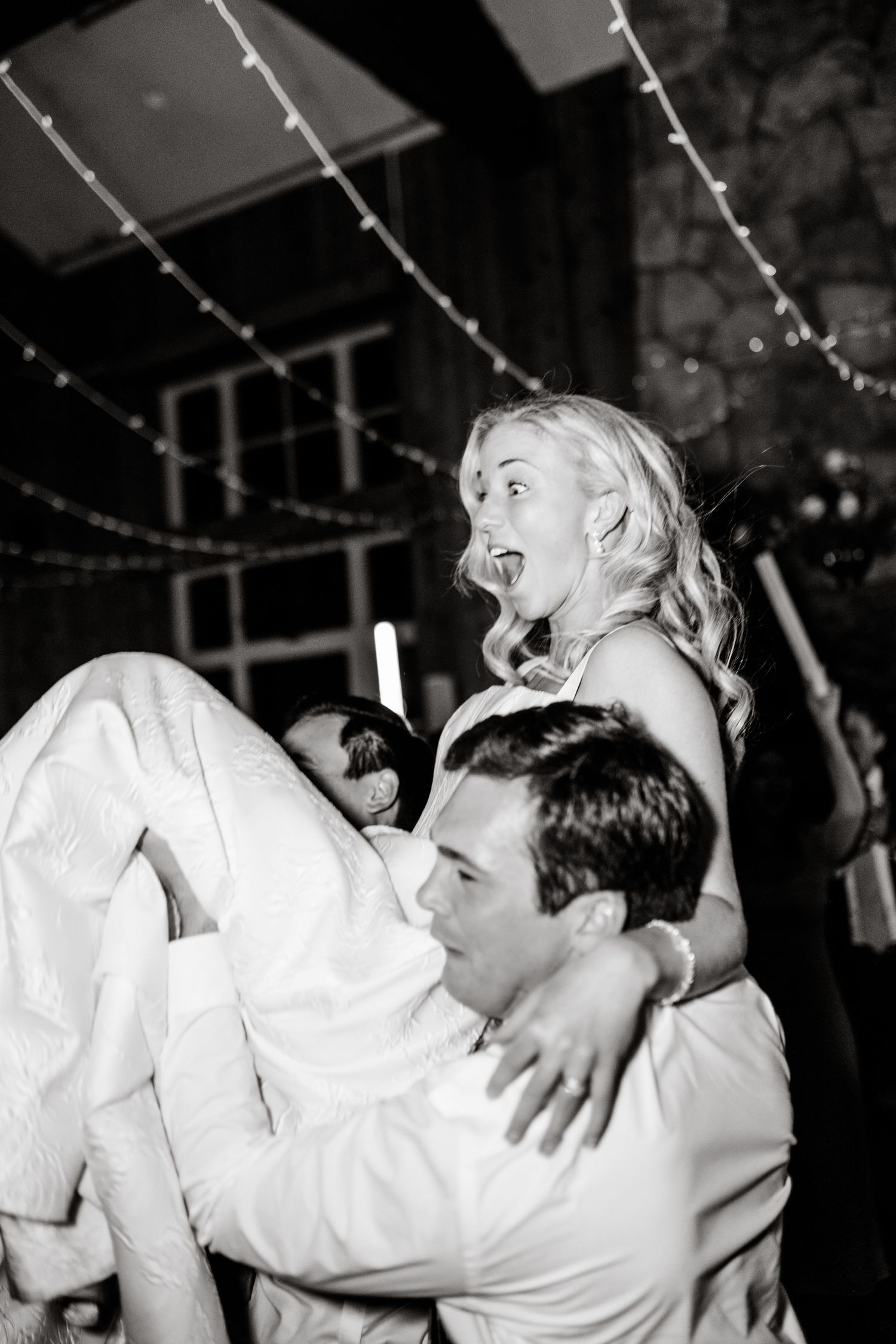 Wedding reception dance moment captured in black and white photography with string lights overhead. Utah Wedding Photographer.