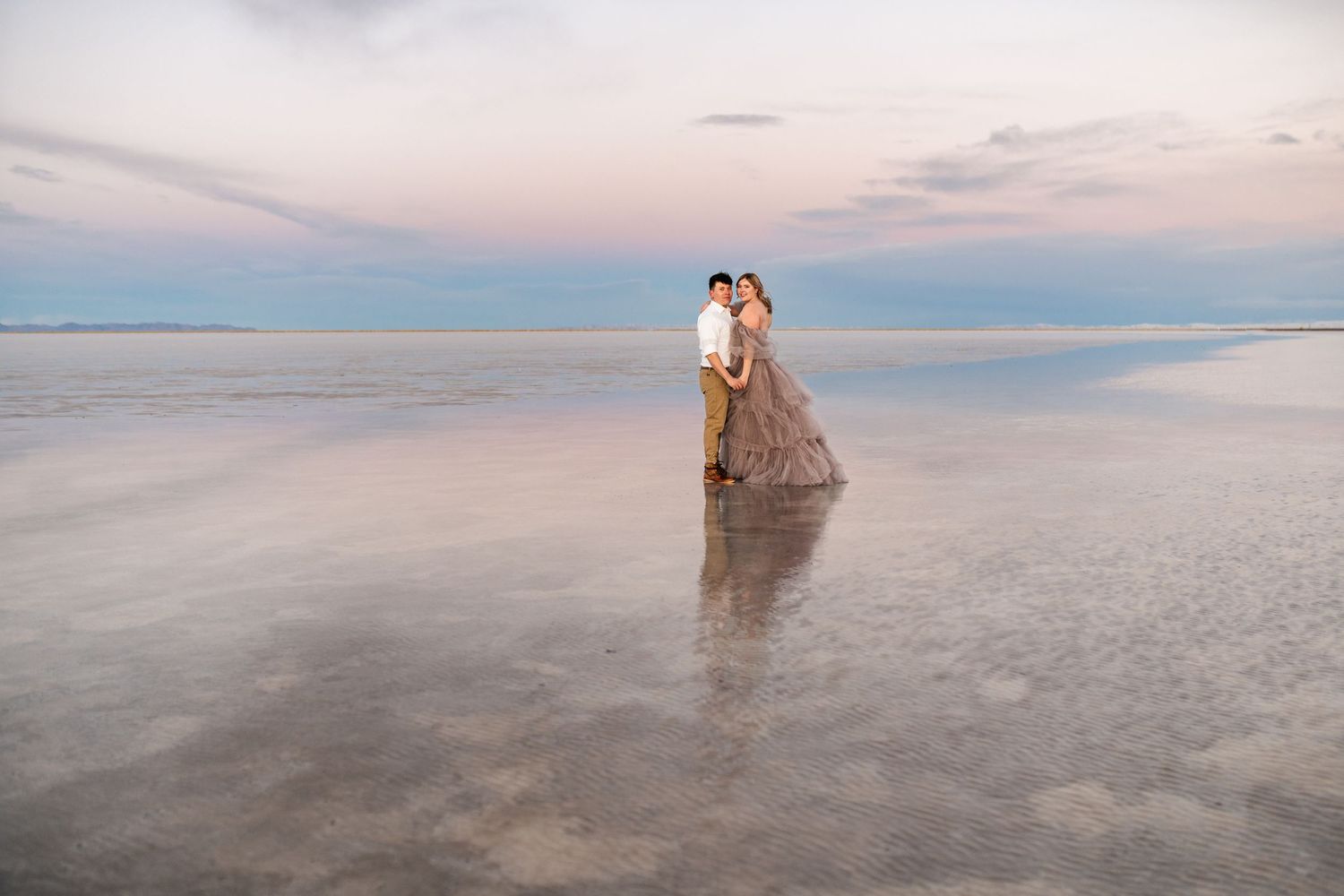 A tender embrace between the couple, illuminated by the soft blue light of blue hour at the Salt Flats.