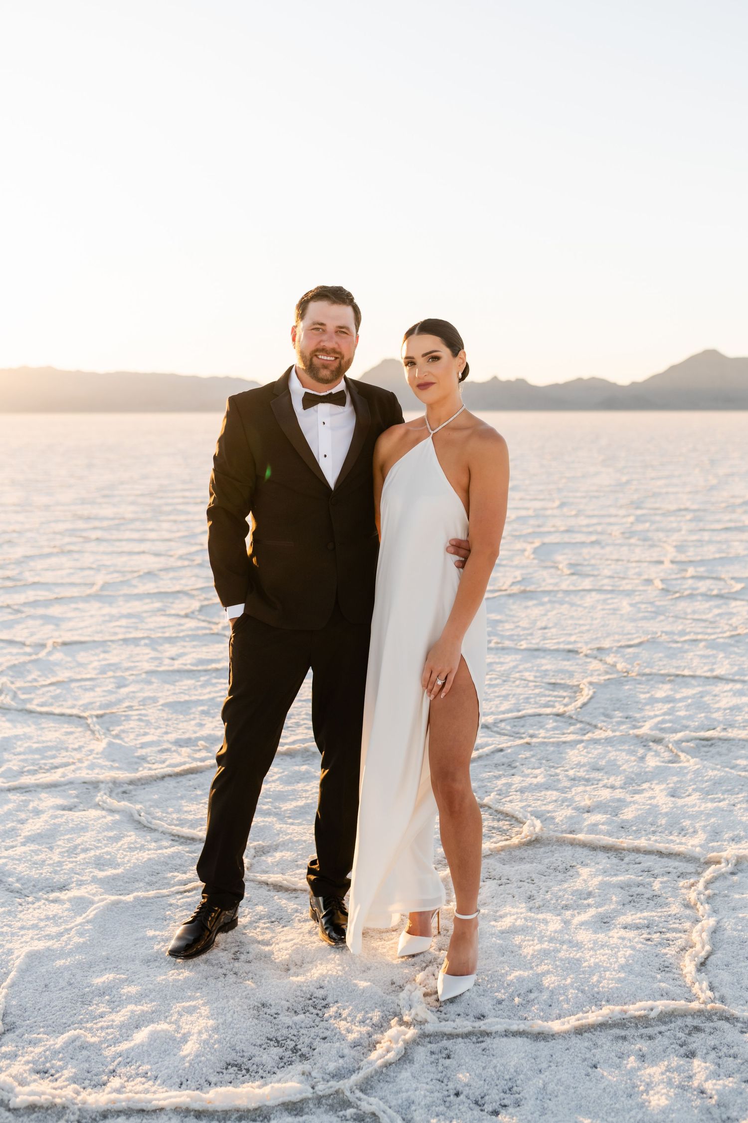 Utah Salt Flats Photographer. A couple in formal attire poses together on the white salt flats during sunset.