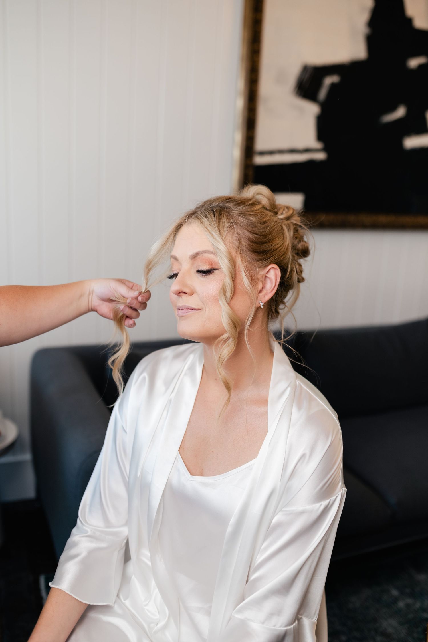 Getting ready scene with someone in a white silk robe sitting on a dark couch.