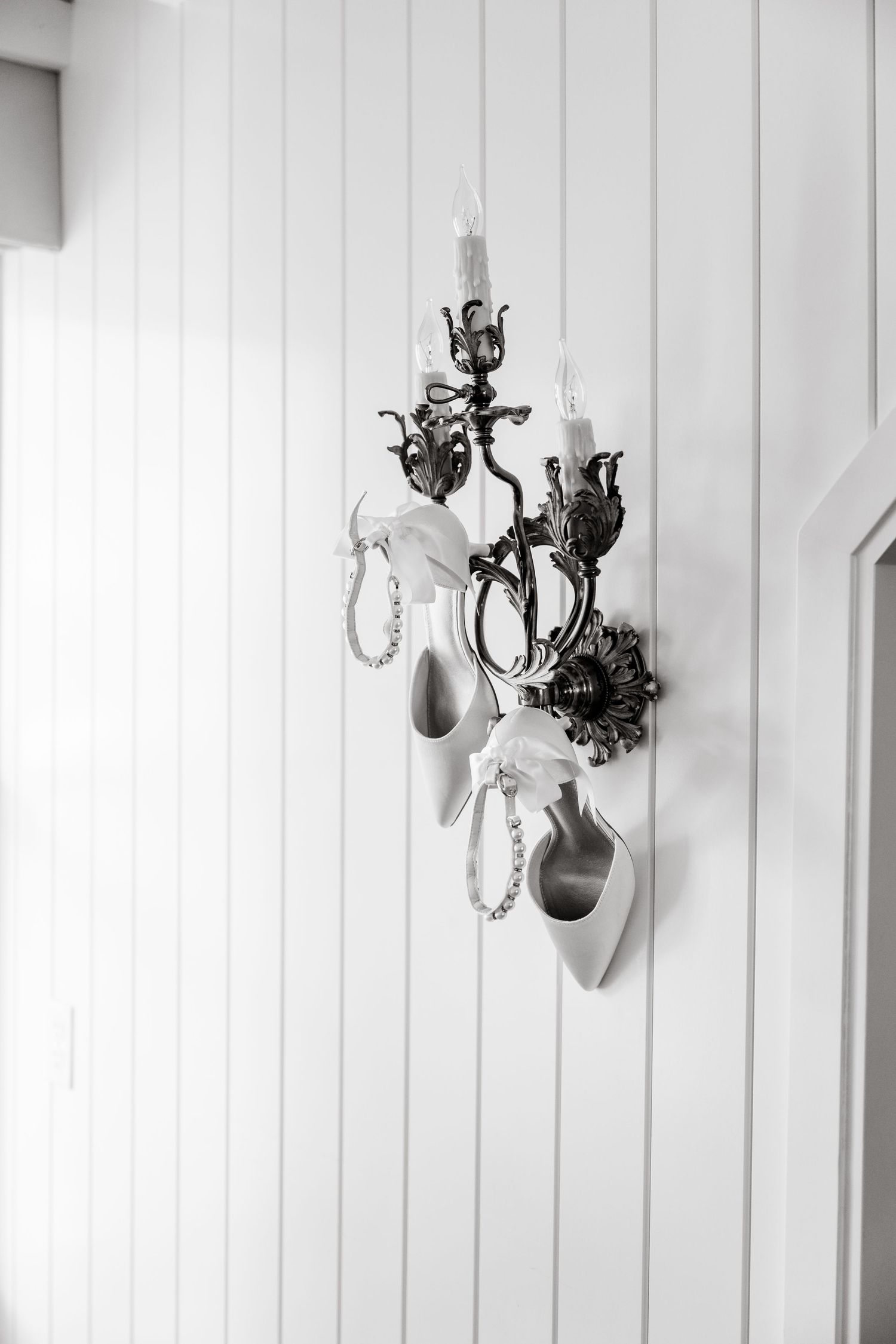 White paneled wall decorated with elegant vintage-style sconces and mounted decor.