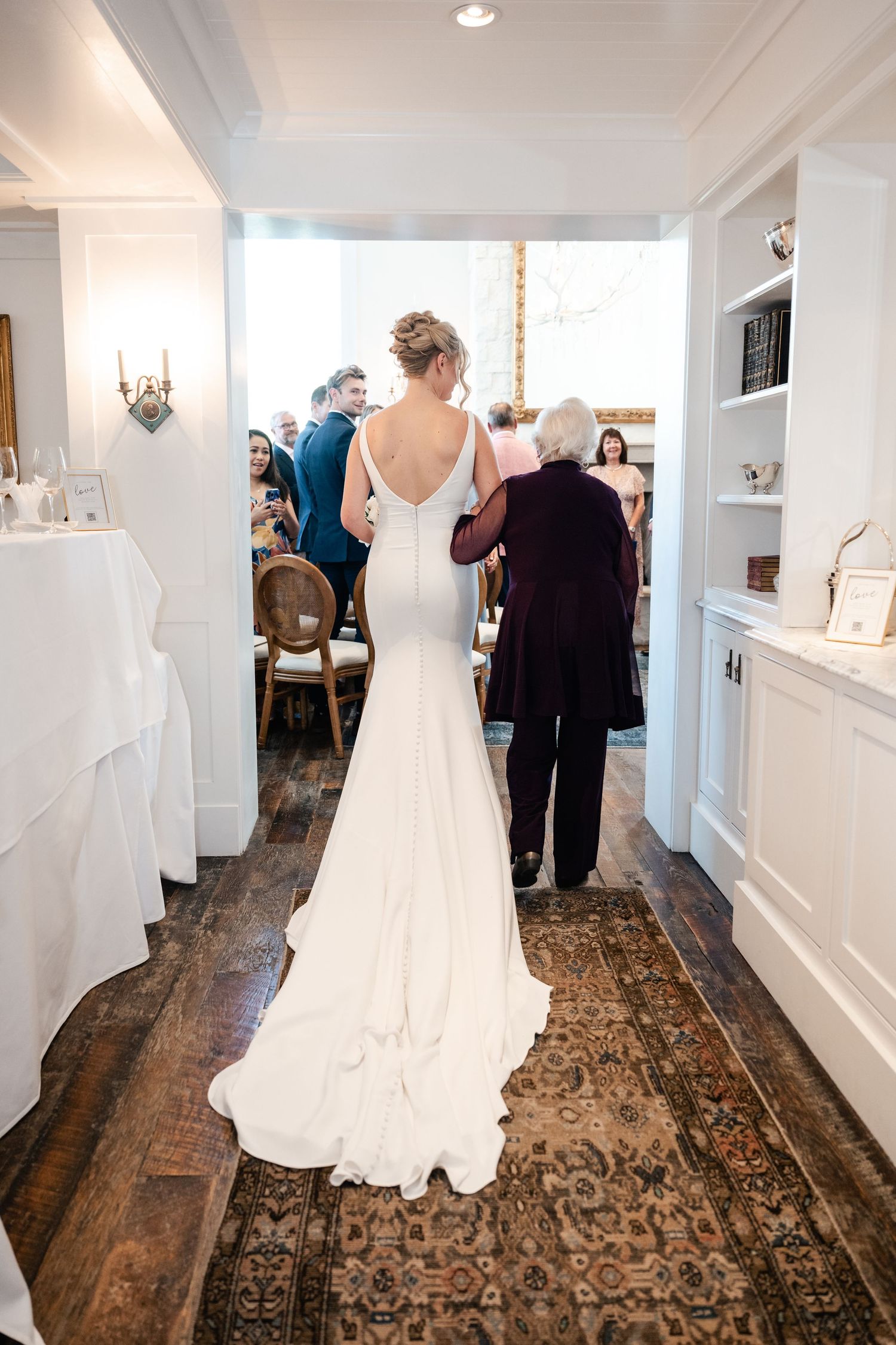 Wedding celebration in an elegant white room with hardwood floors and decorative rugs.