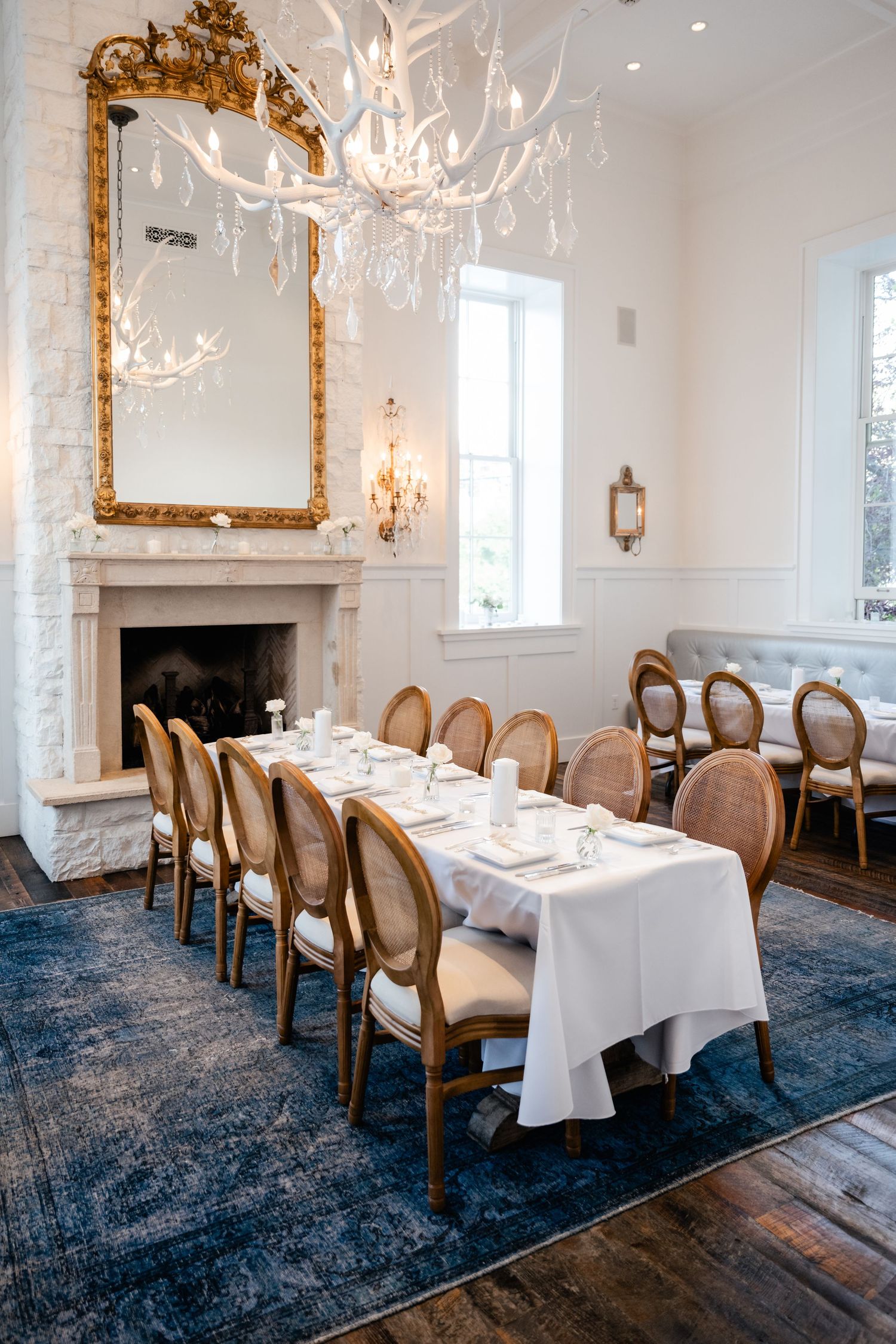 Elegant dining room with antique gold mirror, crystal chandelier and long table set for a formal dinner.