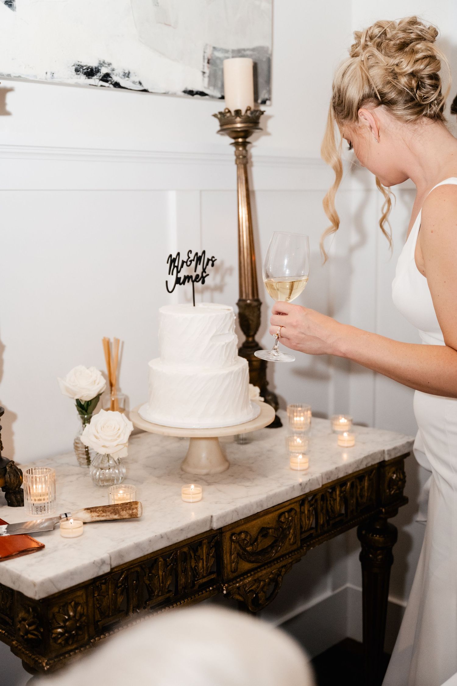 Wedding cake display on an antique wooden table with candles and decorative elements.
