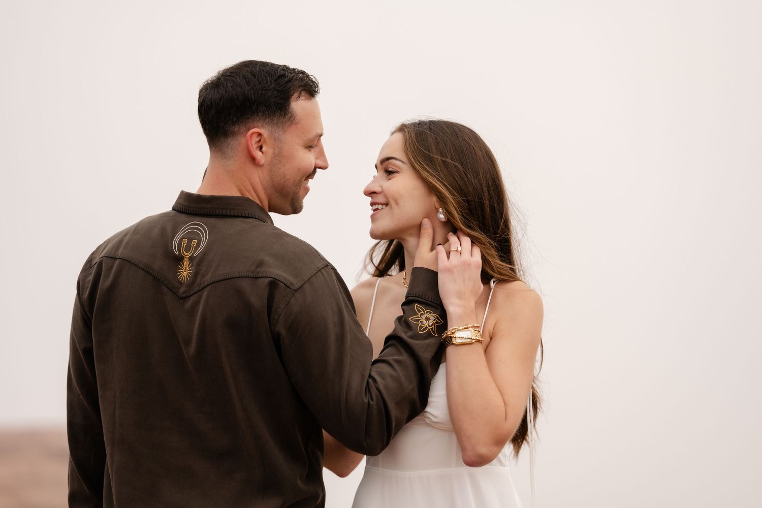Romantic couple in formal attire embracing in a desert landscape during golden hour.