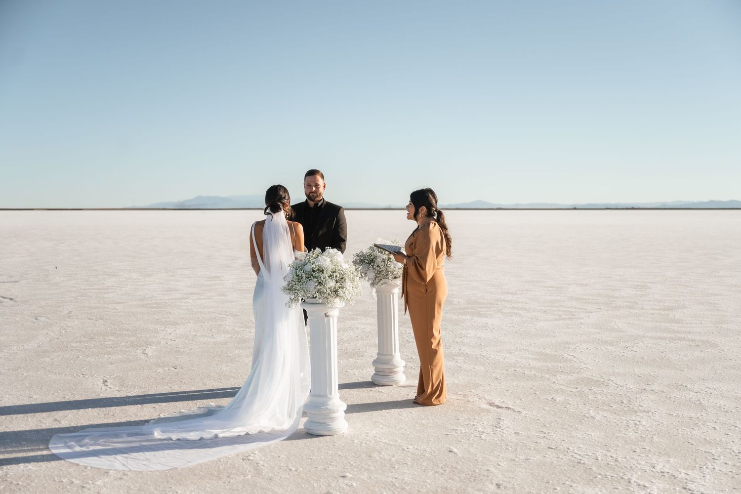 Wedding photography session on vast white salt flats under clear blue sky.