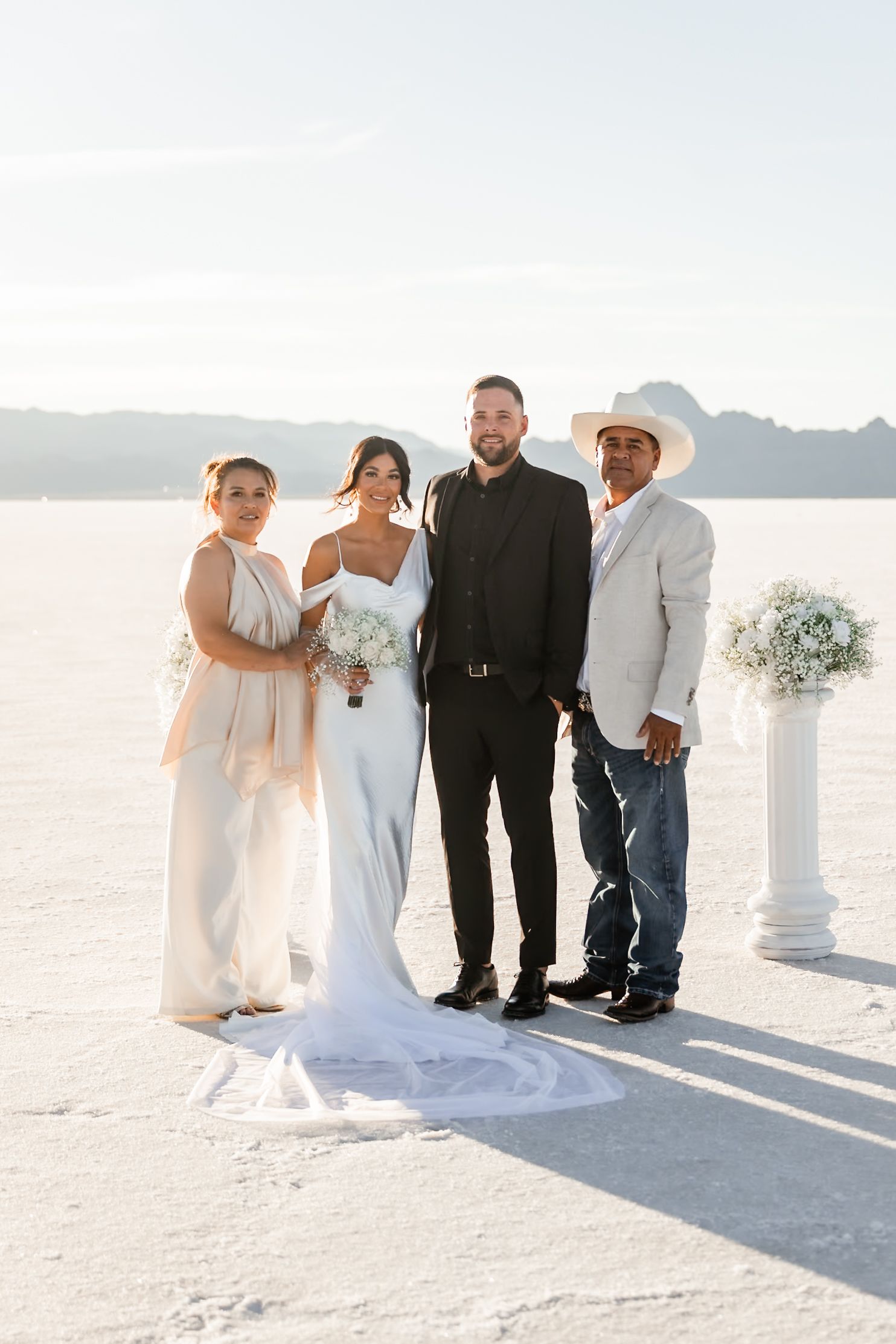 A wedding party poses together on the bright white salt flats during a sunset ceremony.