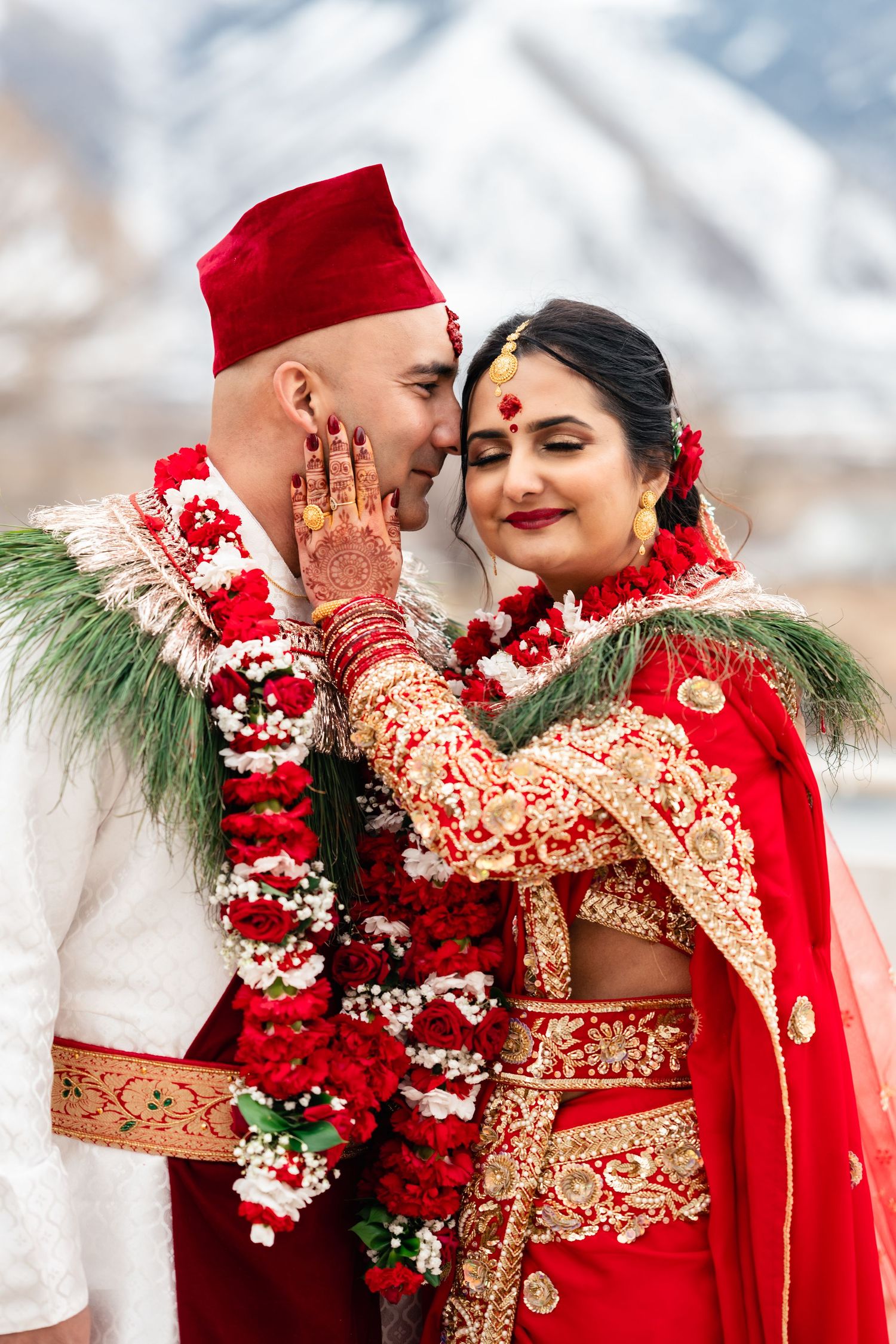 A romantic winter wedding scene featuring a couple in traditional red and gold at the Krishna temple in Spanish Fork. Utah Indian Wedding.