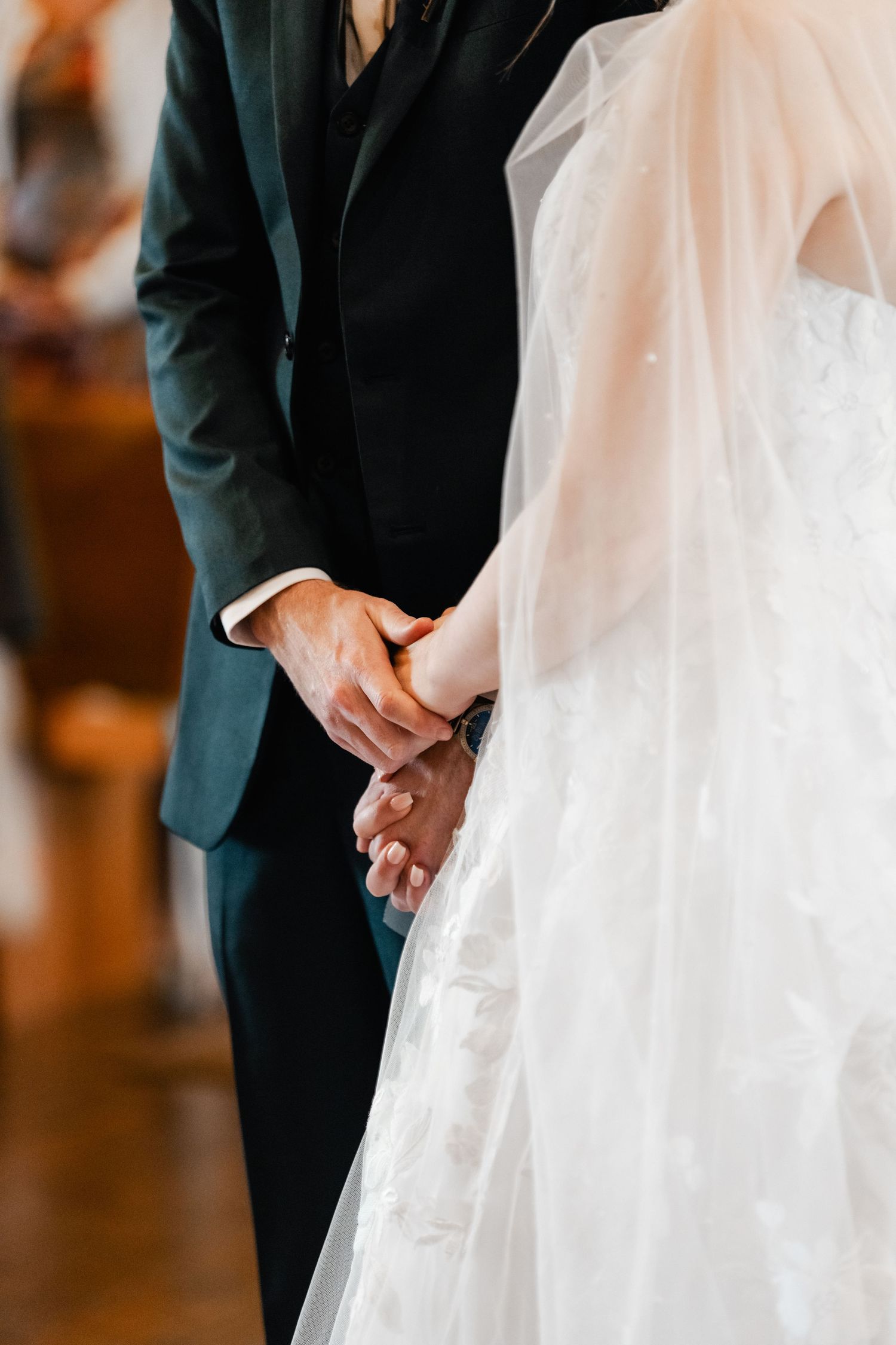 Detail shot of hands and flowing white wedding dress fabric during ceremony.