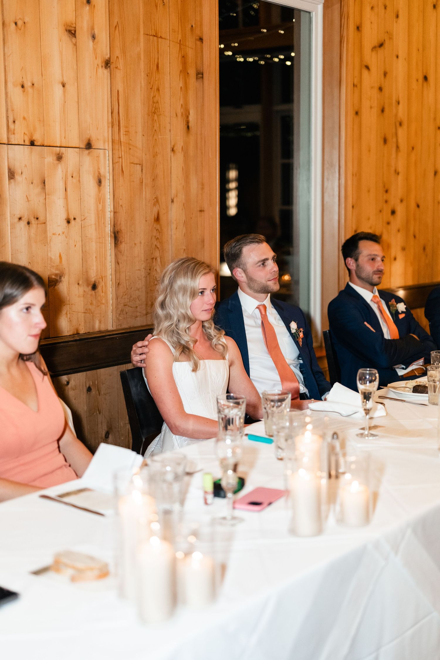 Wedding reception dinner in rustic wooden venue with guests seated at long tables.