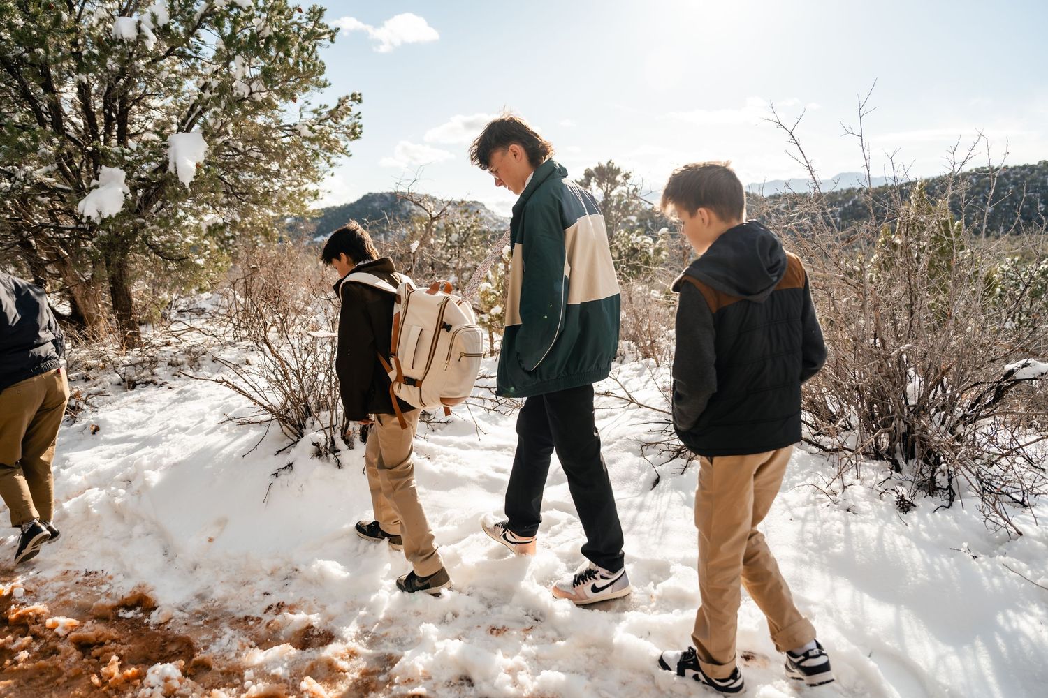 Group walking through fresh snow with desert rock formations visible in distance.