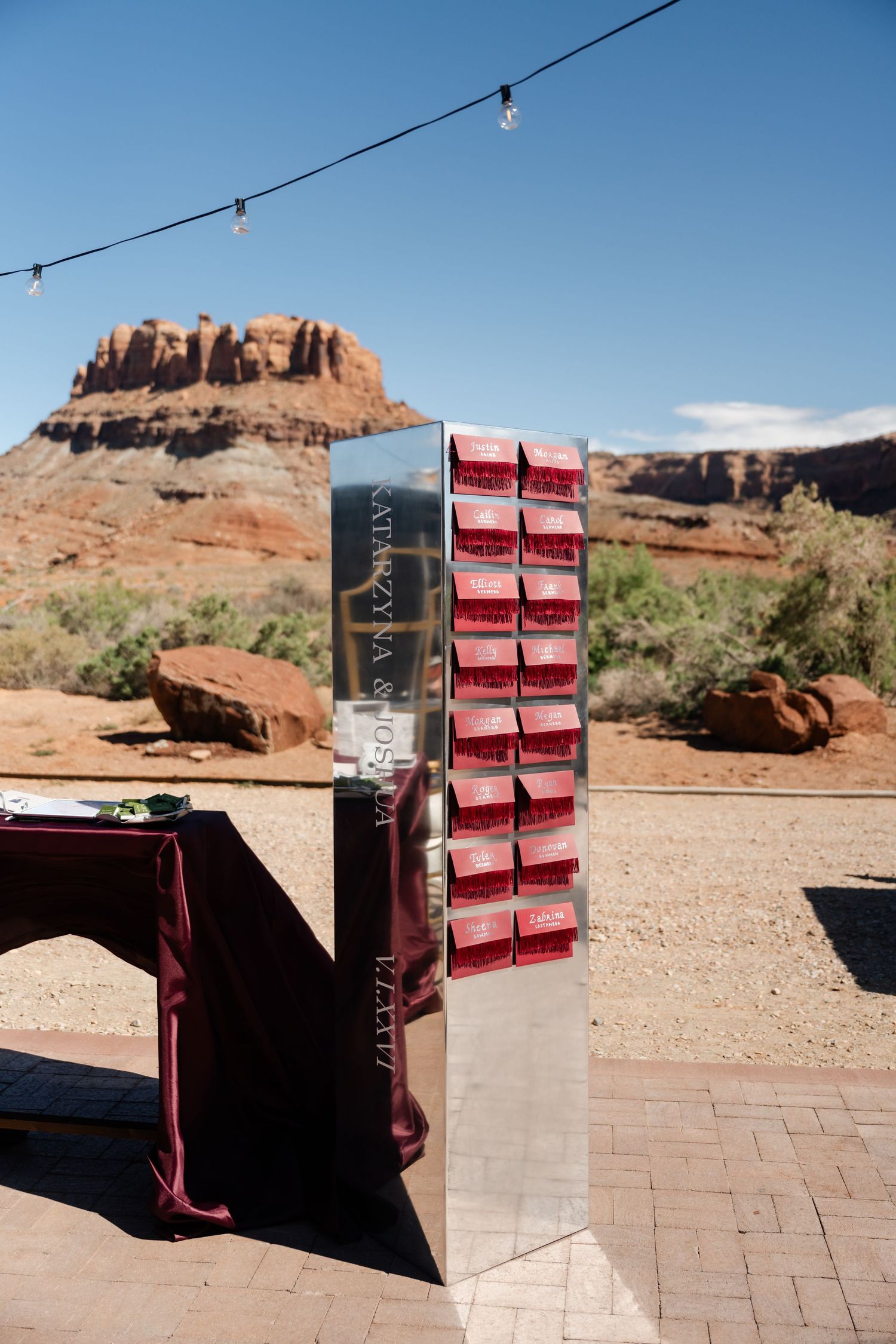 Mirrored seating chart display with red card holders at an outdoor desert wedding venue in Sedona, Arizona red rock landscape.