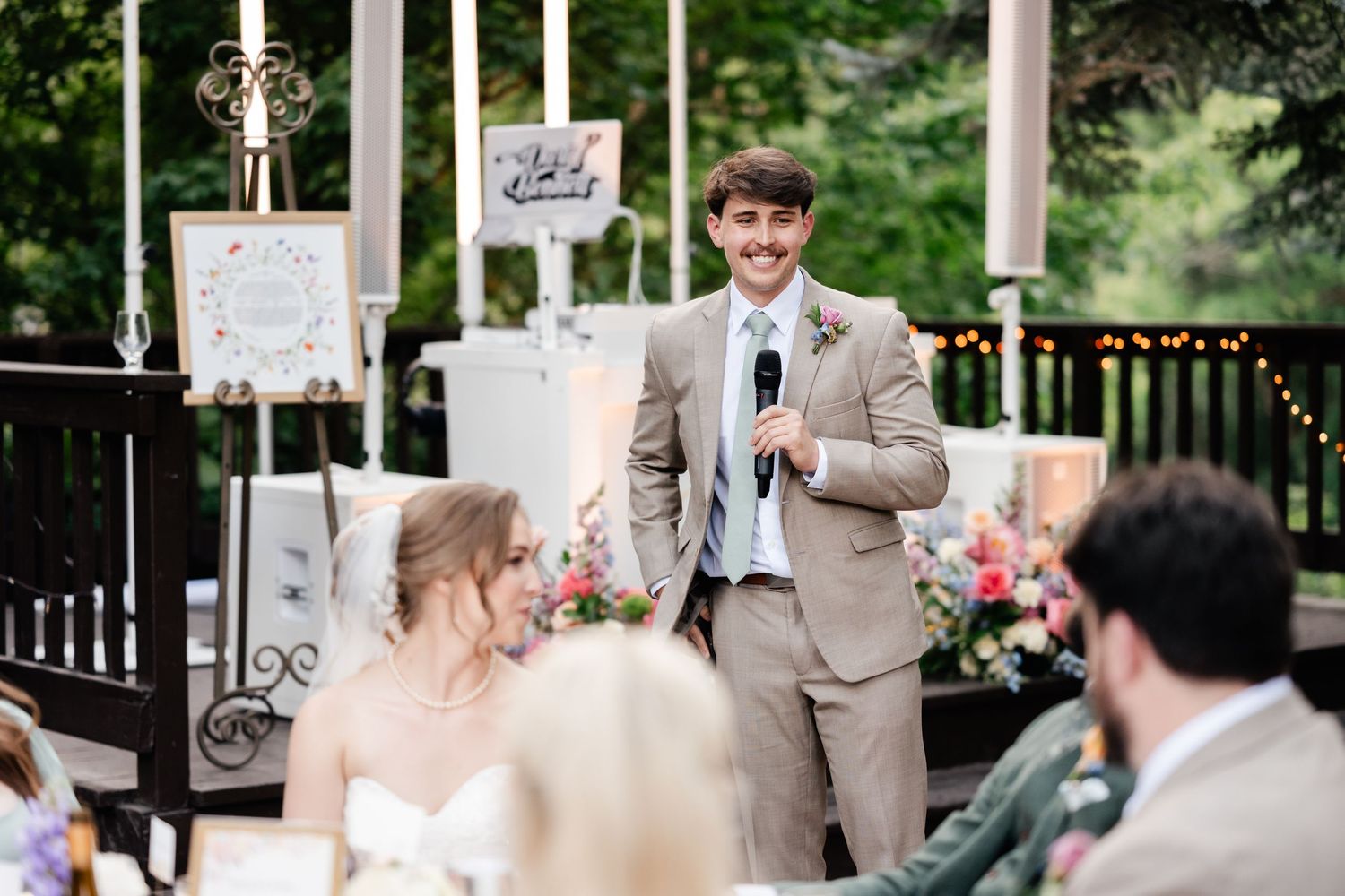 A couple exchanges vows during an outdoor garden wedding ceremony surrounded by lush greenery and string lights. Utah Mountain Wedding.