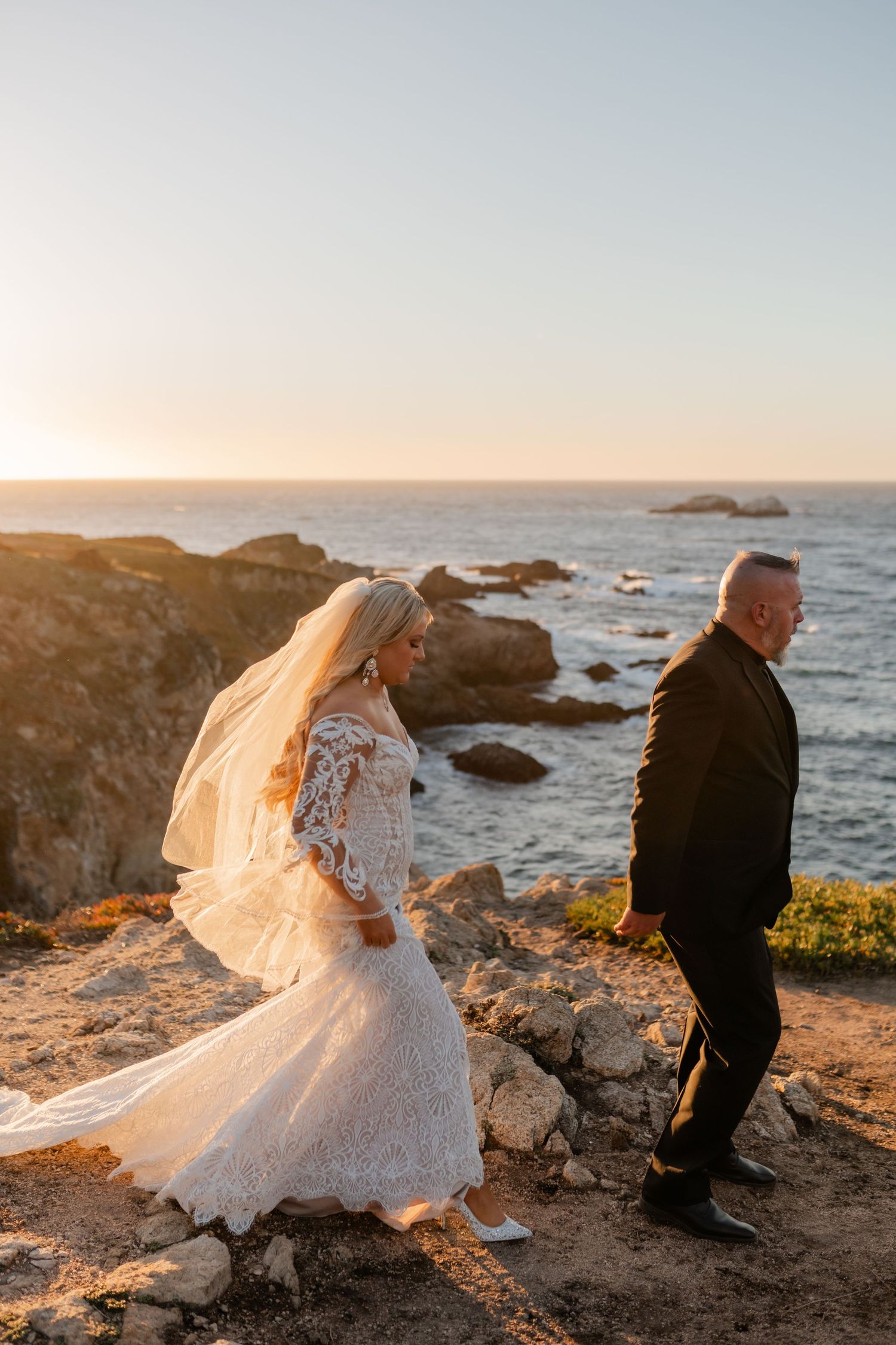 Sunset wedding photography session on dramatic coastal cliffs with crashing waves in the background.