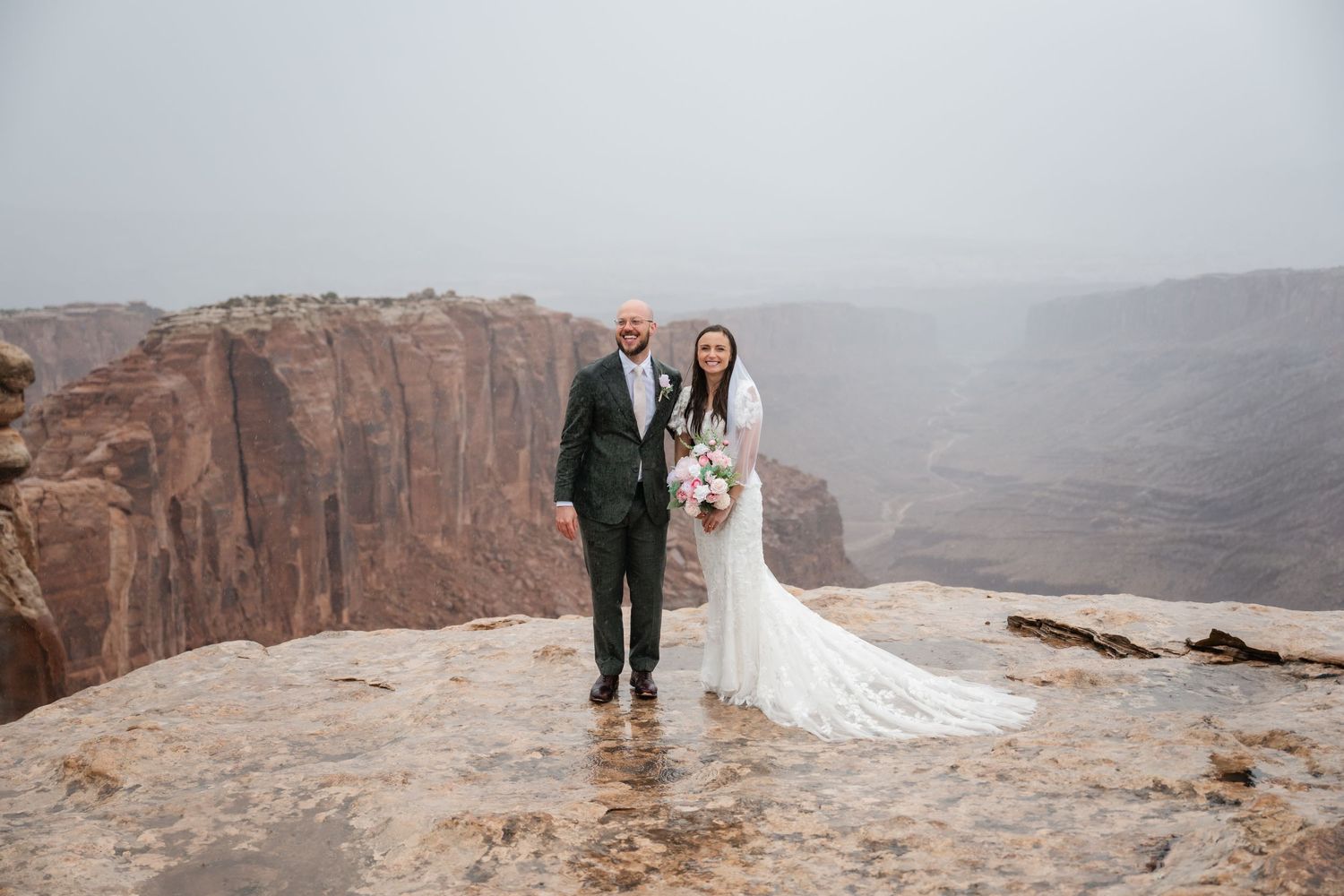 Wedding ceremony overlooking majestic desert canyon on cloudy day.