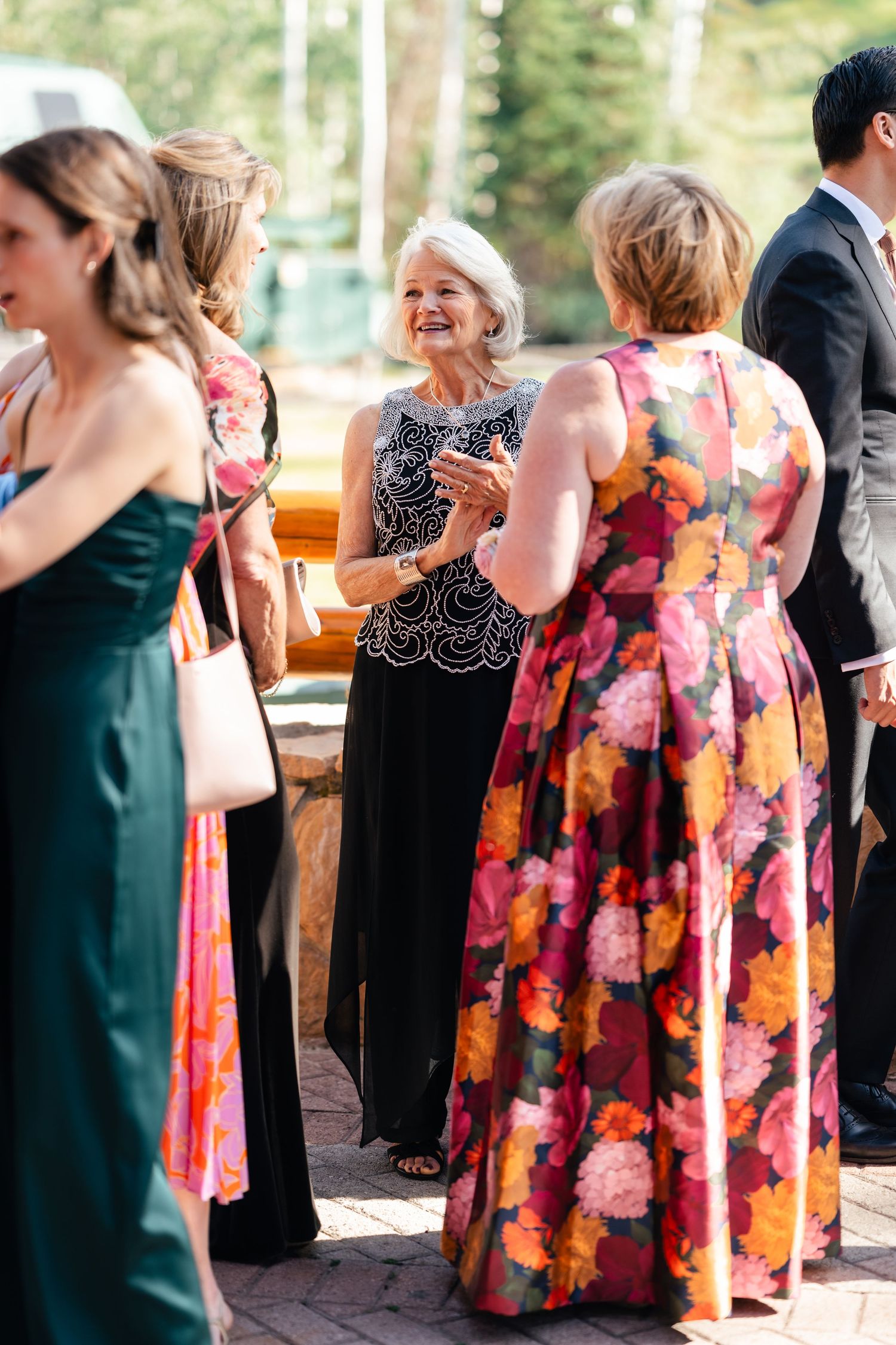 Guests mingling at an outdoor wedding reception wearing colorful formal attire.