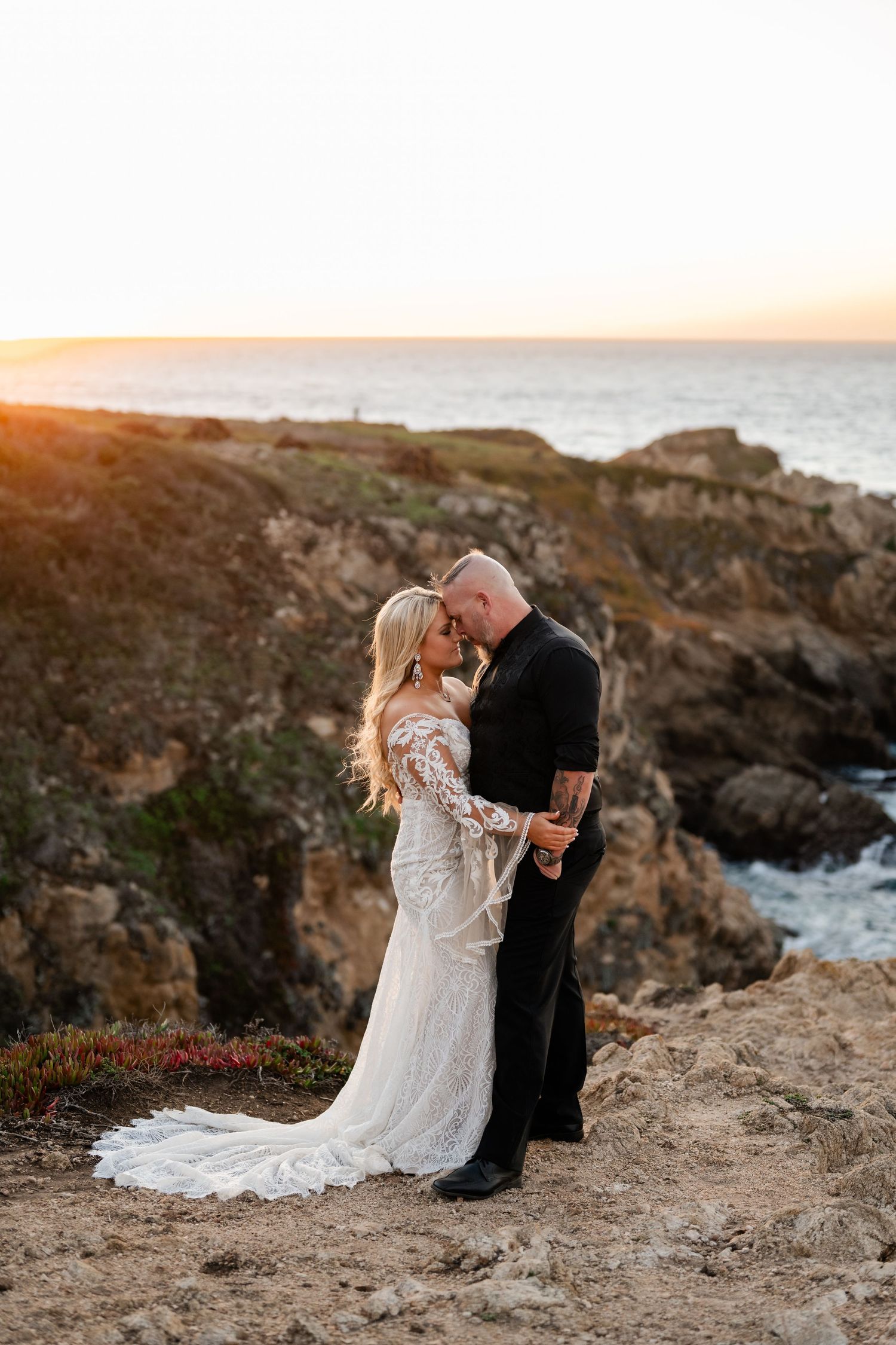 A romantic sunset wedding portrait captured on dramatic coastal cliffs by the ocean.