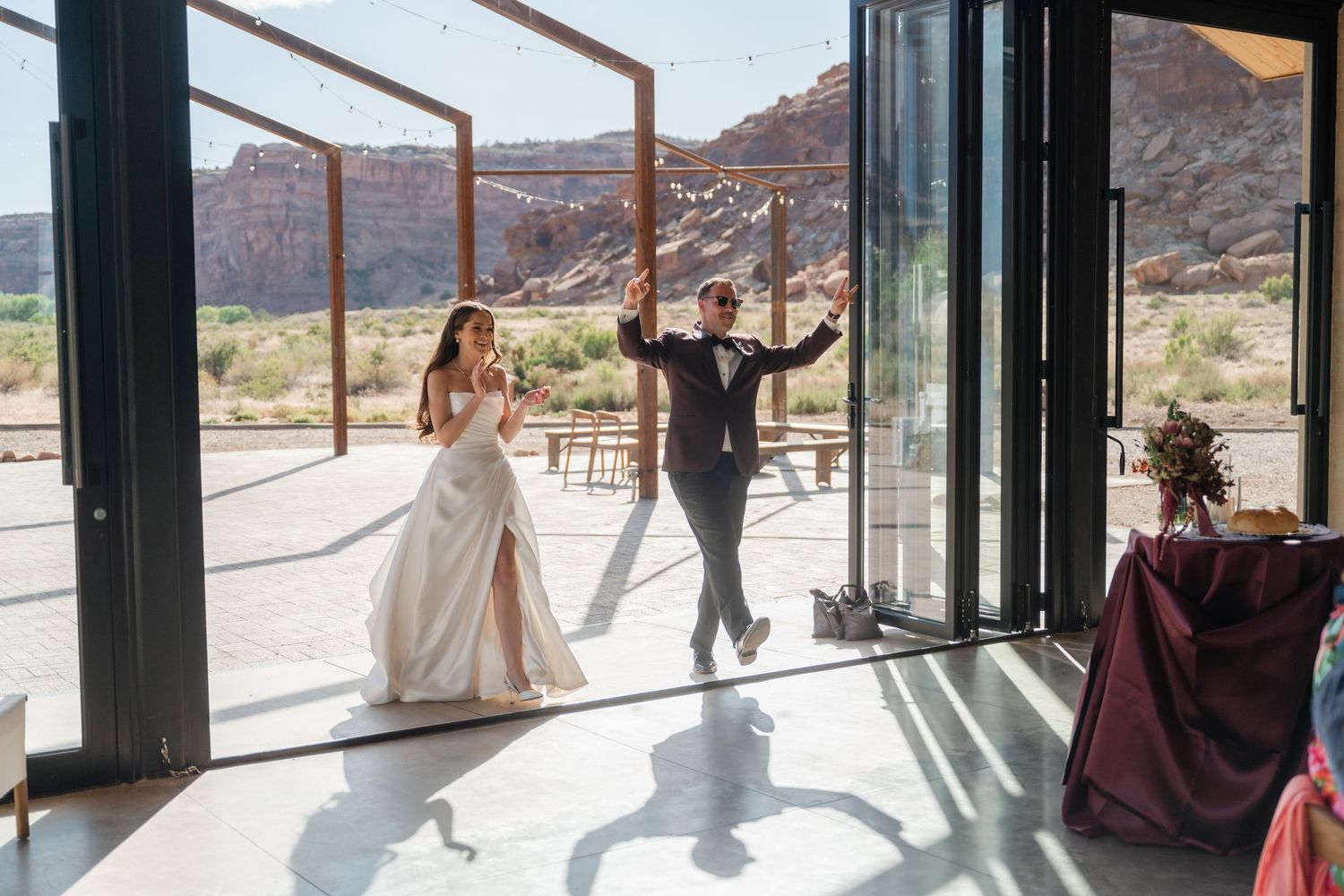 Bride and groom make grand entrance into modern desert wedding venue with red rock canyon views.