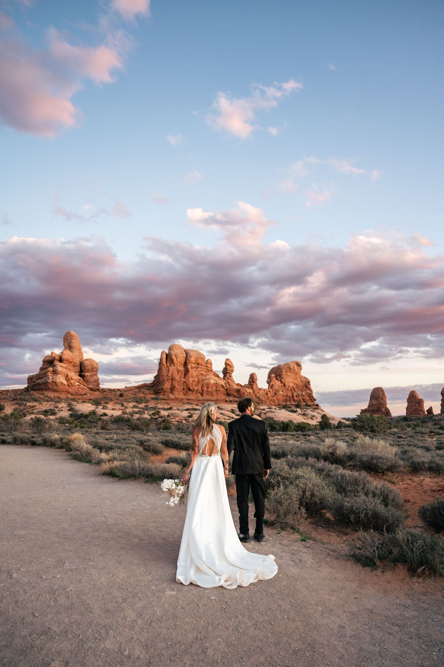Elopement couple hold hands in Arches National Park by Utah Elopement Photographer and videographer