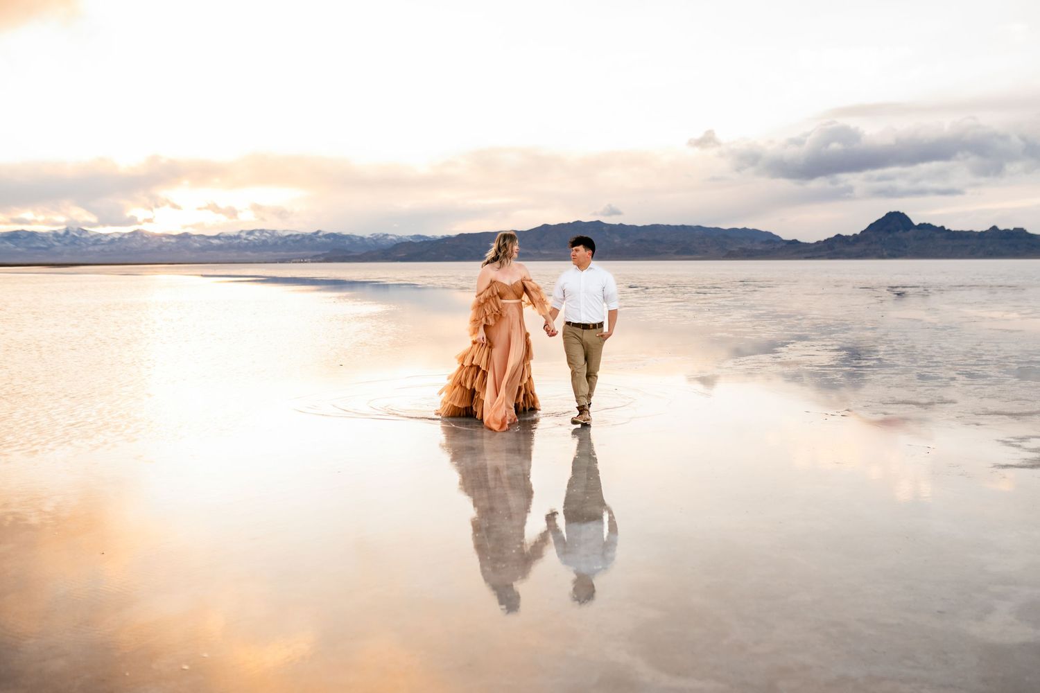 The flooded Salt Flats provides a captivating backdrop for a couple's photo session during golden hour