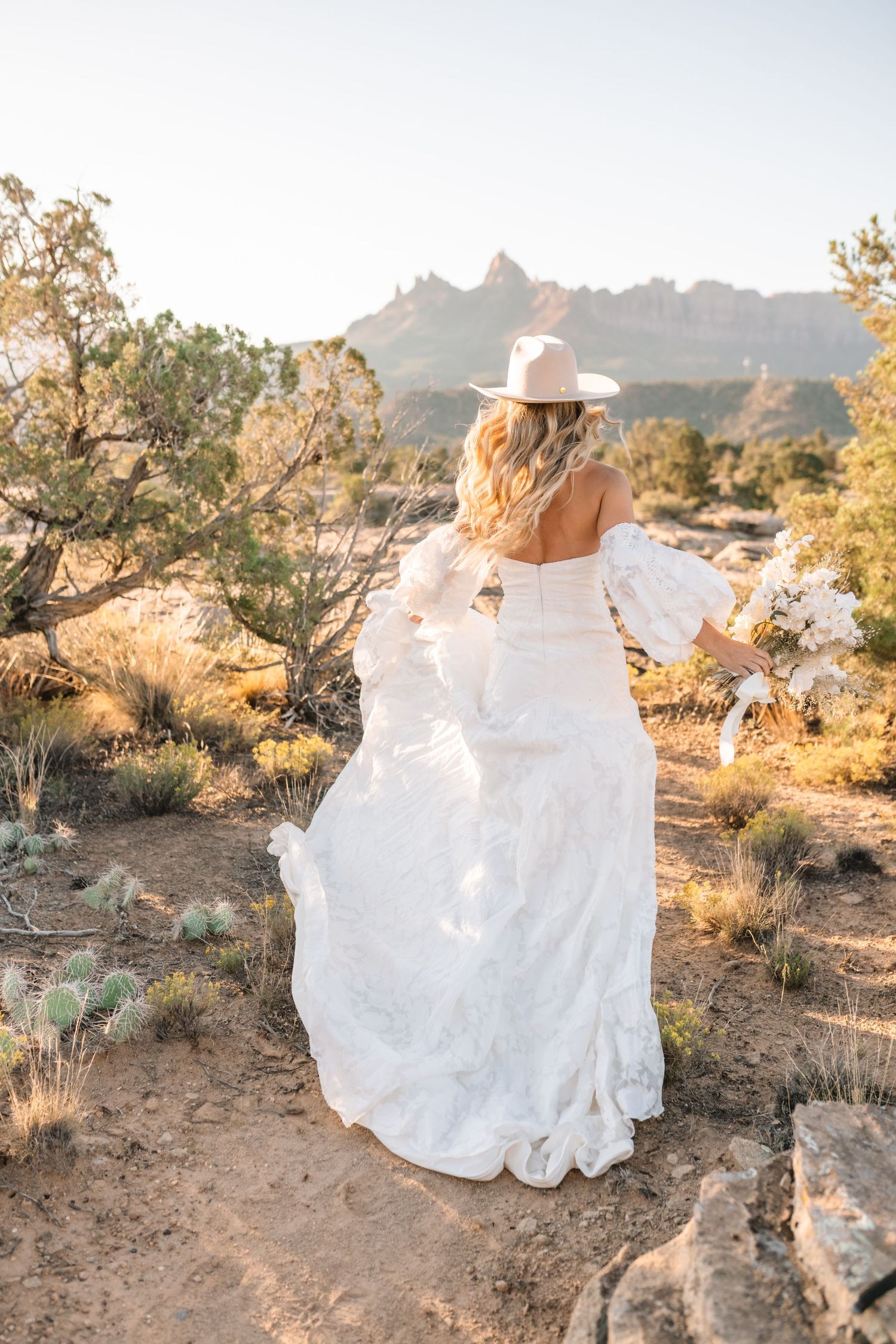 Utah elopement photographer takes breathtaking desert sunrise bridal session with a stunning bouquet and cowgirl hat.