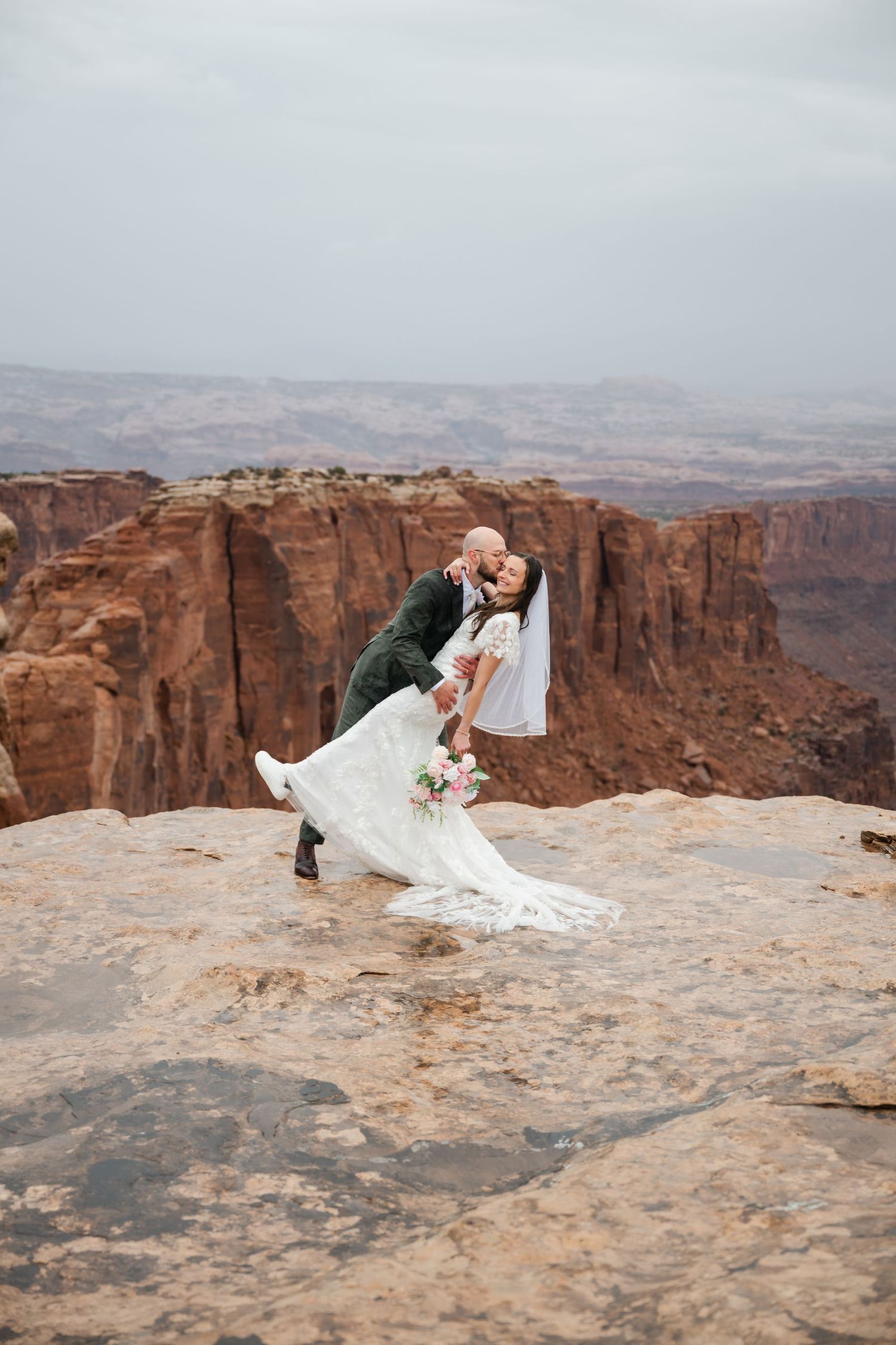 A romantic wedding photoshoot sequence on a dramatic cliff edge overlooking red rock canyons in the desert.