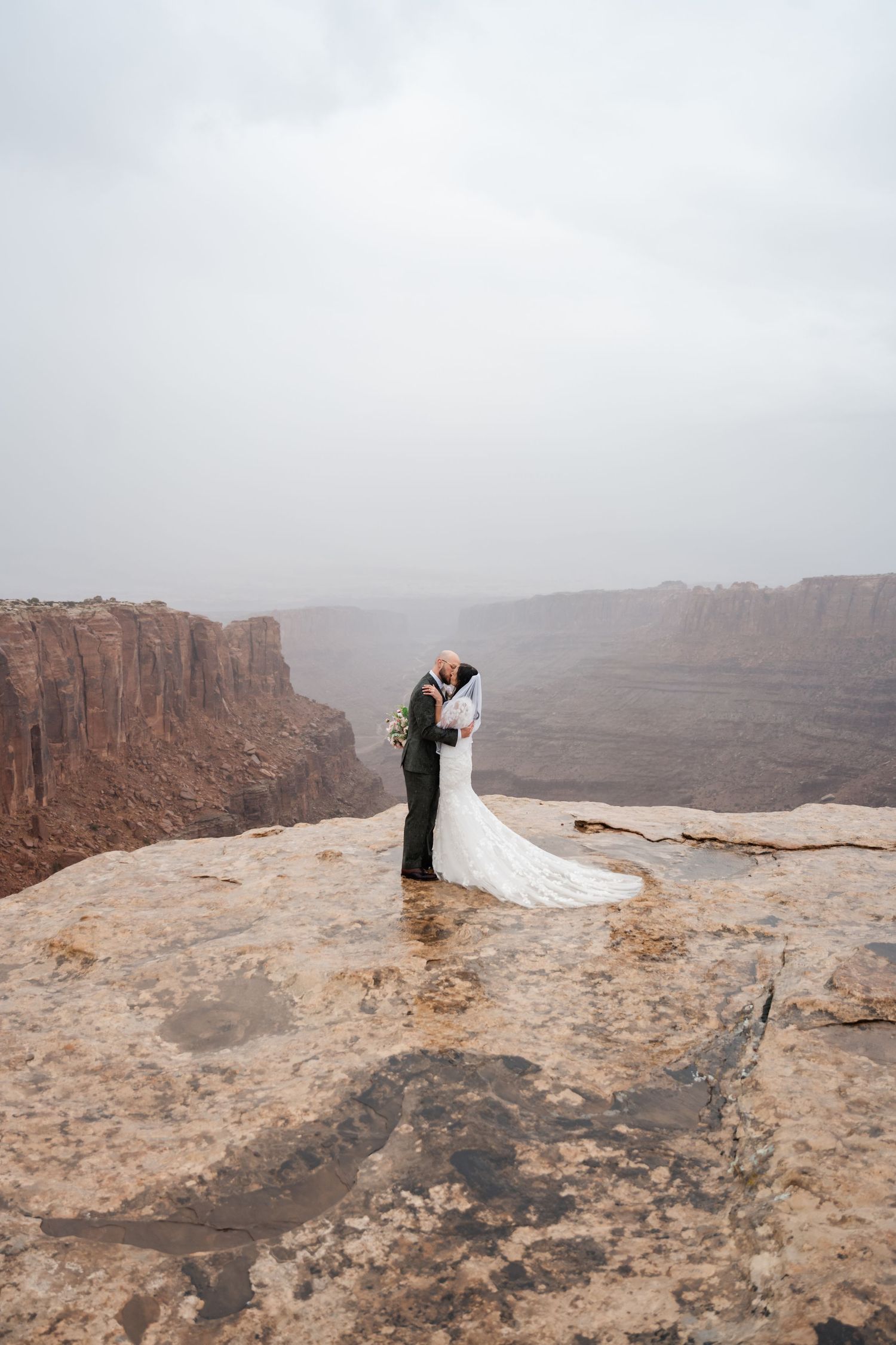 Dramatic cliff edge wedding ceremony with vast canyon views in the background.
