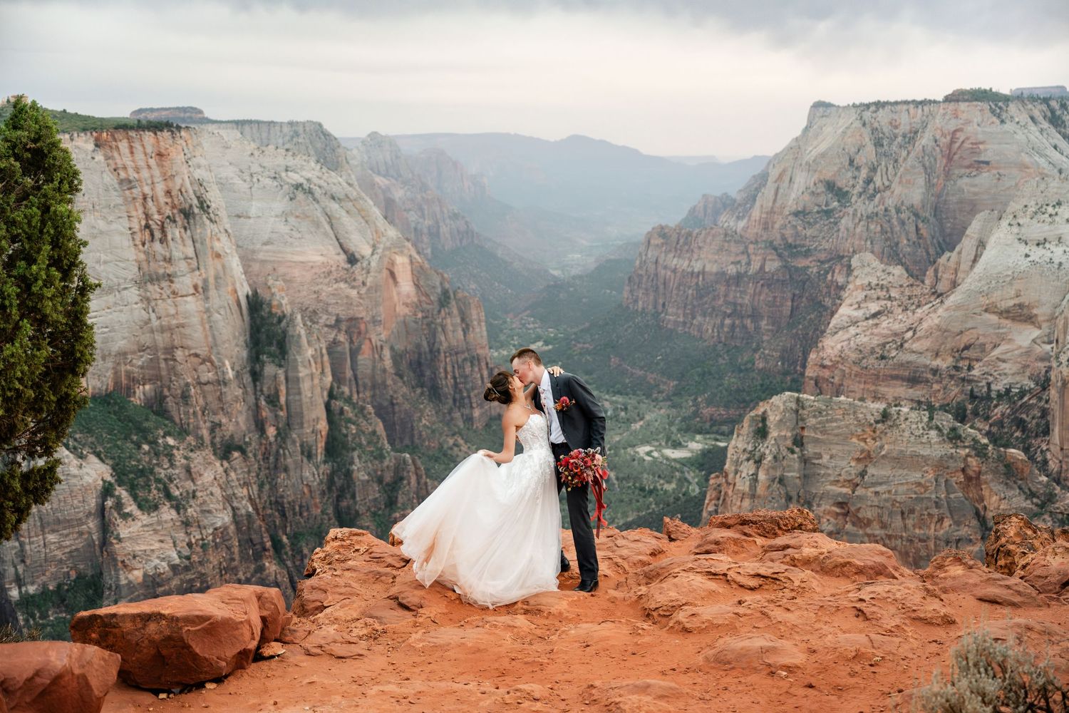 A couple shares a romantic moment on the red cliffs overlooking the dramatic canyons at Zion National Park.