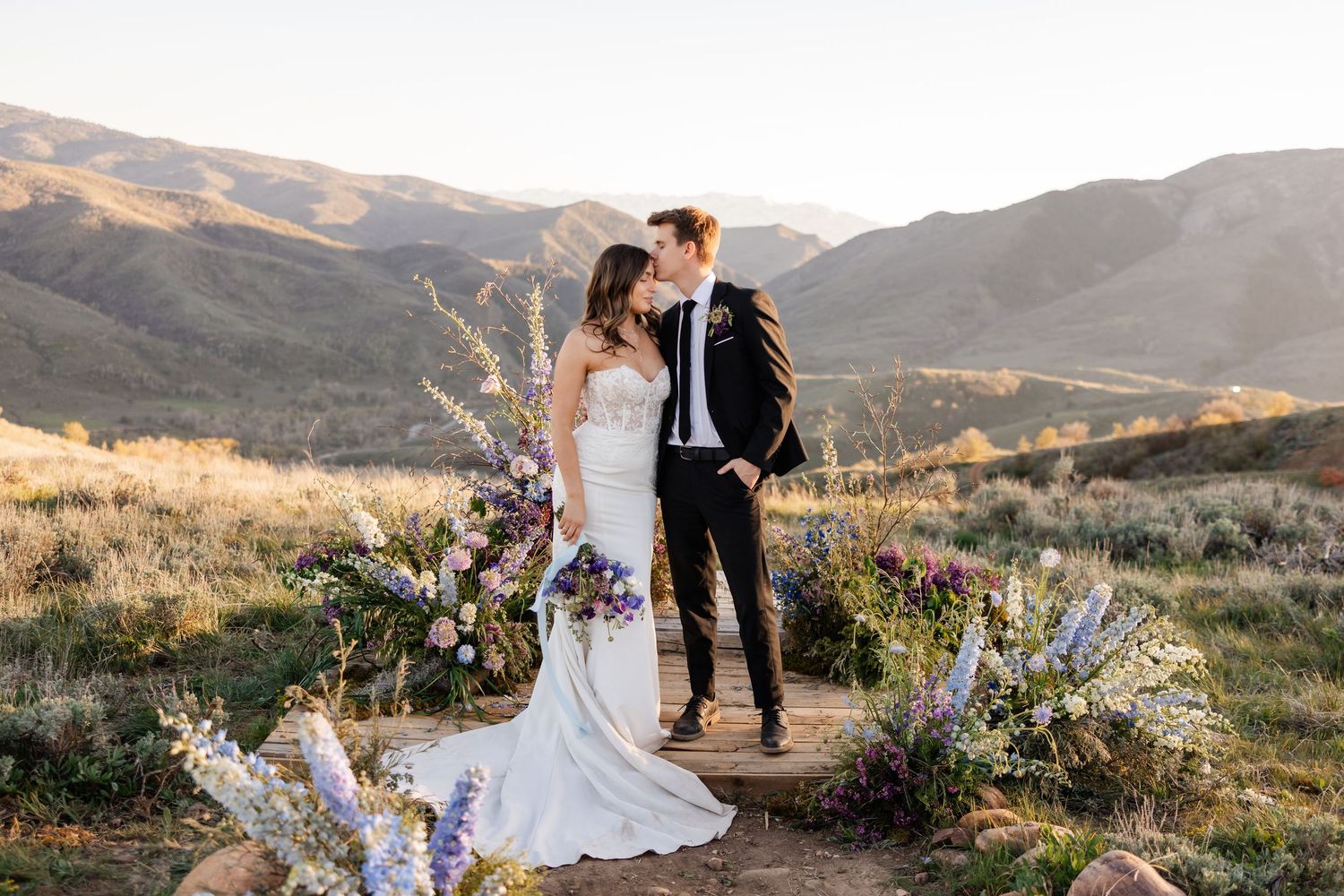 An eloping couple embraces on a scenic mountain hillside during golden hour. Utah elopement photographer. Utah mountain elopement.