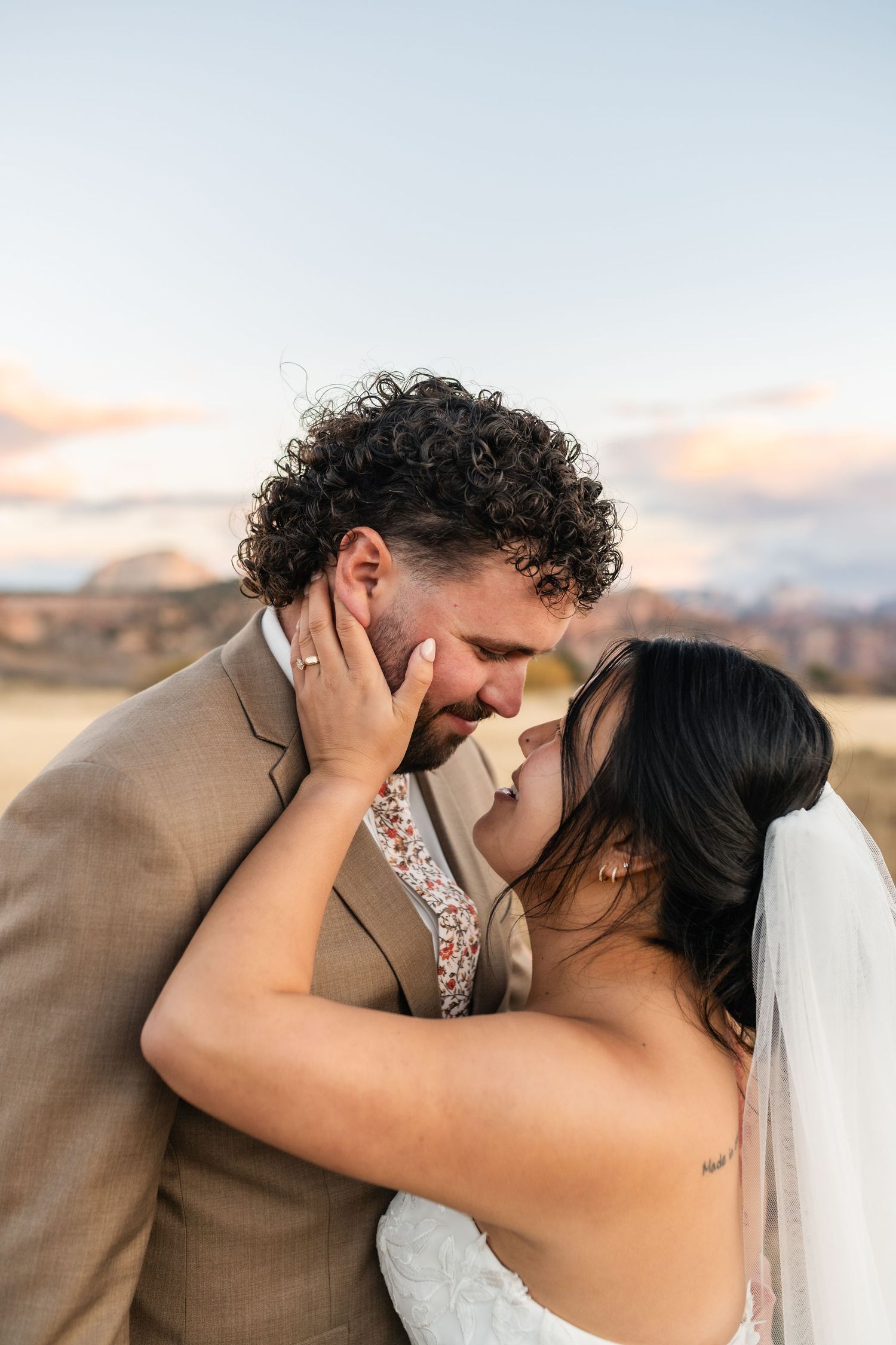 A tender moment between newlyweds sharing a kiss during their outdoor mountain wedding.