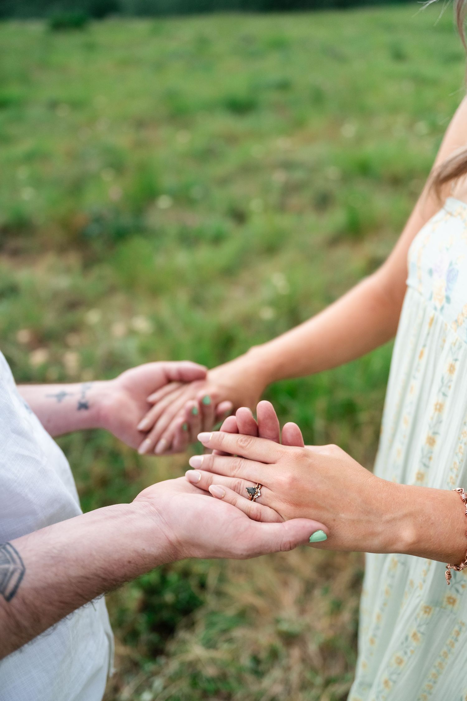A series of close-up shots showing hands during a romantic proposal moment in a grassy outdoor setting.