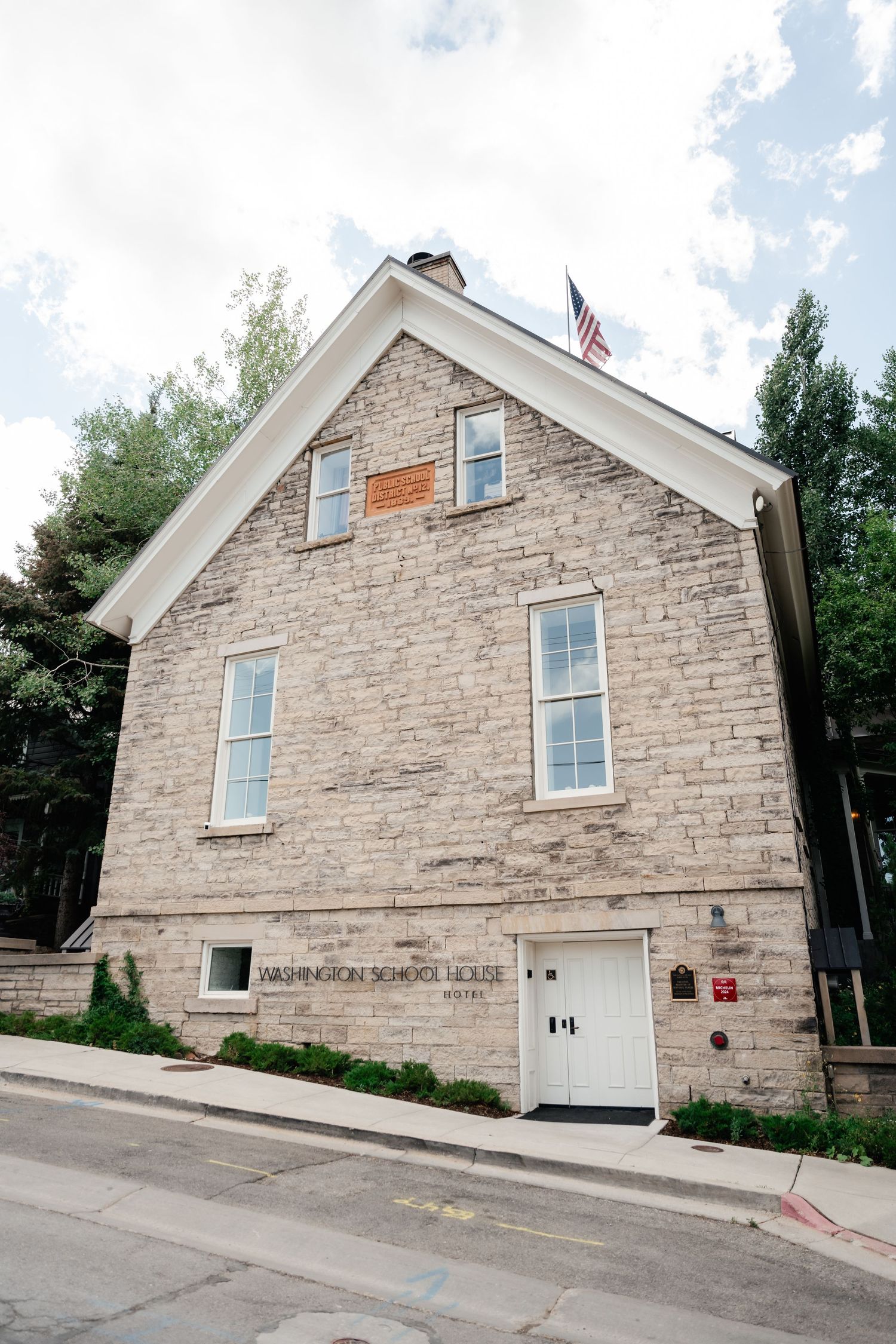 Exterior view of Washington School Lodge, a historic stone building with white trim and windows on a sloping street.