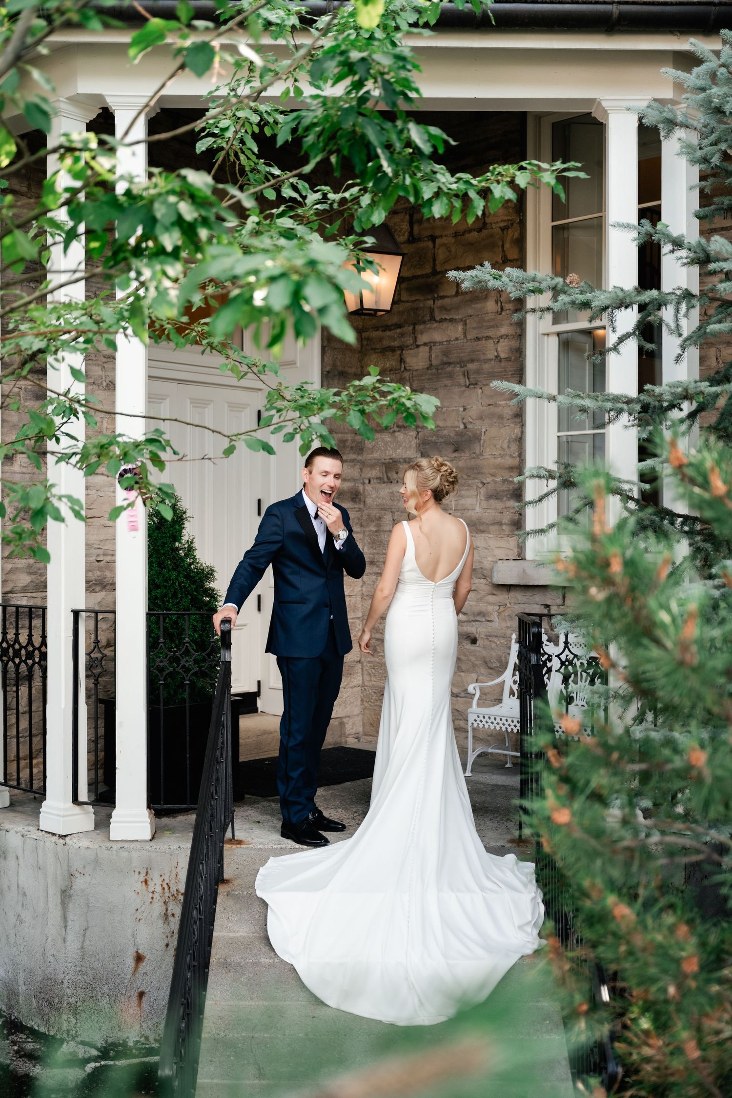 Newlyweds dance together on an elegant stone porch surrounded by lush foliage.