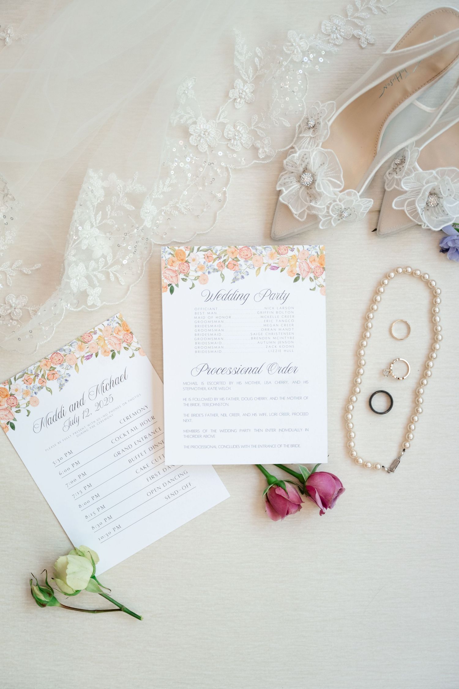 Wedding stationery flat lay with invitation cards, rings, and pink flower petals on light background. Park City Wedding Photographer.