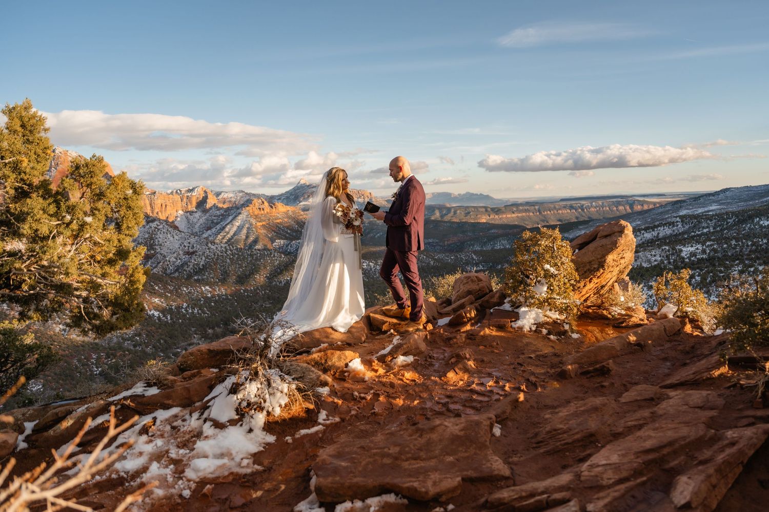 Scenic mountain landscape with snow patches and red rock formations at sunset.