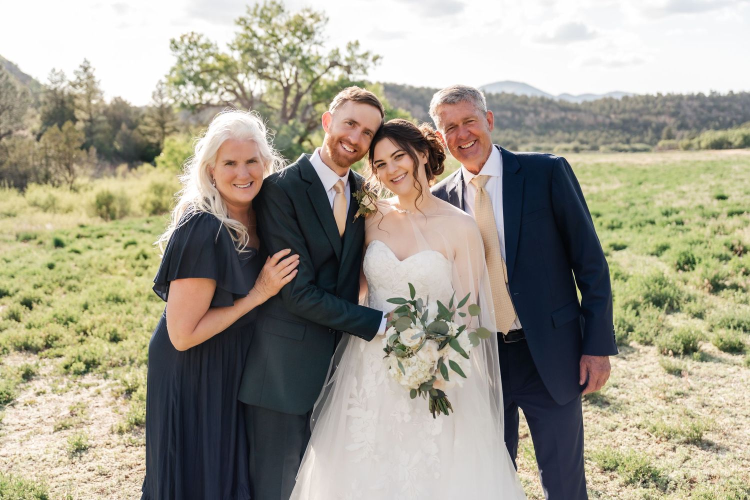 A wedding party poses together in an outdoor desert landscape setting with mountains in the background.