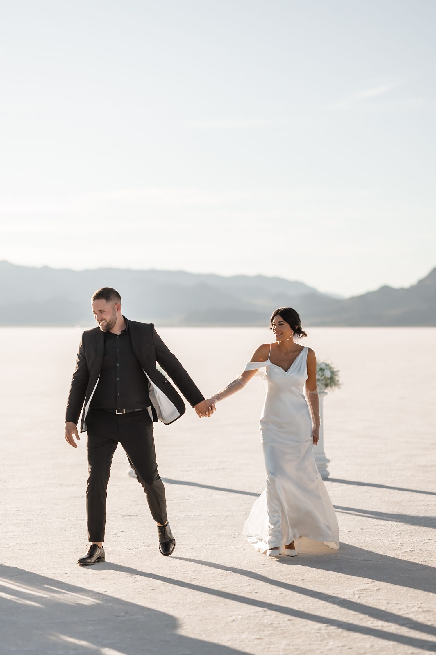 Playful wedding couple dancing and posing on bright white salt flats.