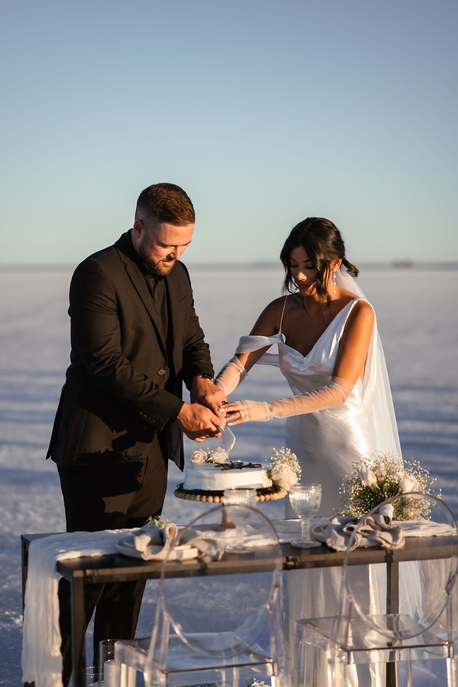 A couple signs their marriage certificate at an elegant white table on the salt flats.