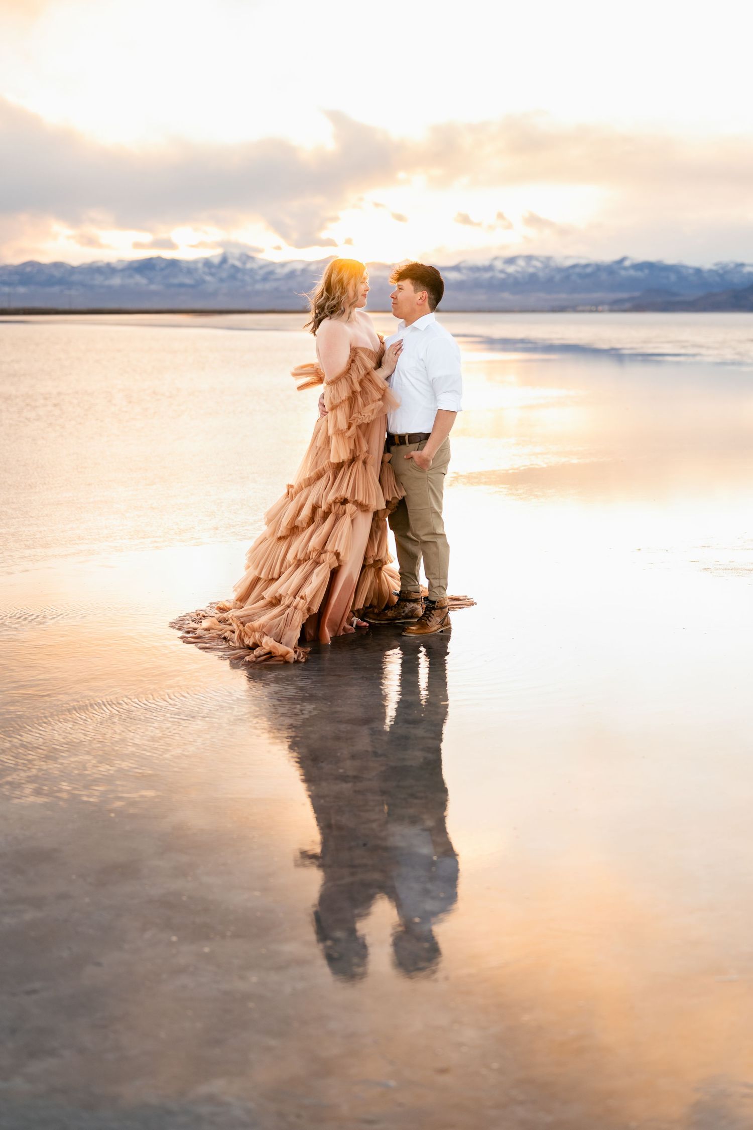 Utah Salt Flats Photographer. A couple dances together on a reflective salt flat at sunset creating a dreamy mirror effect in the landscape.