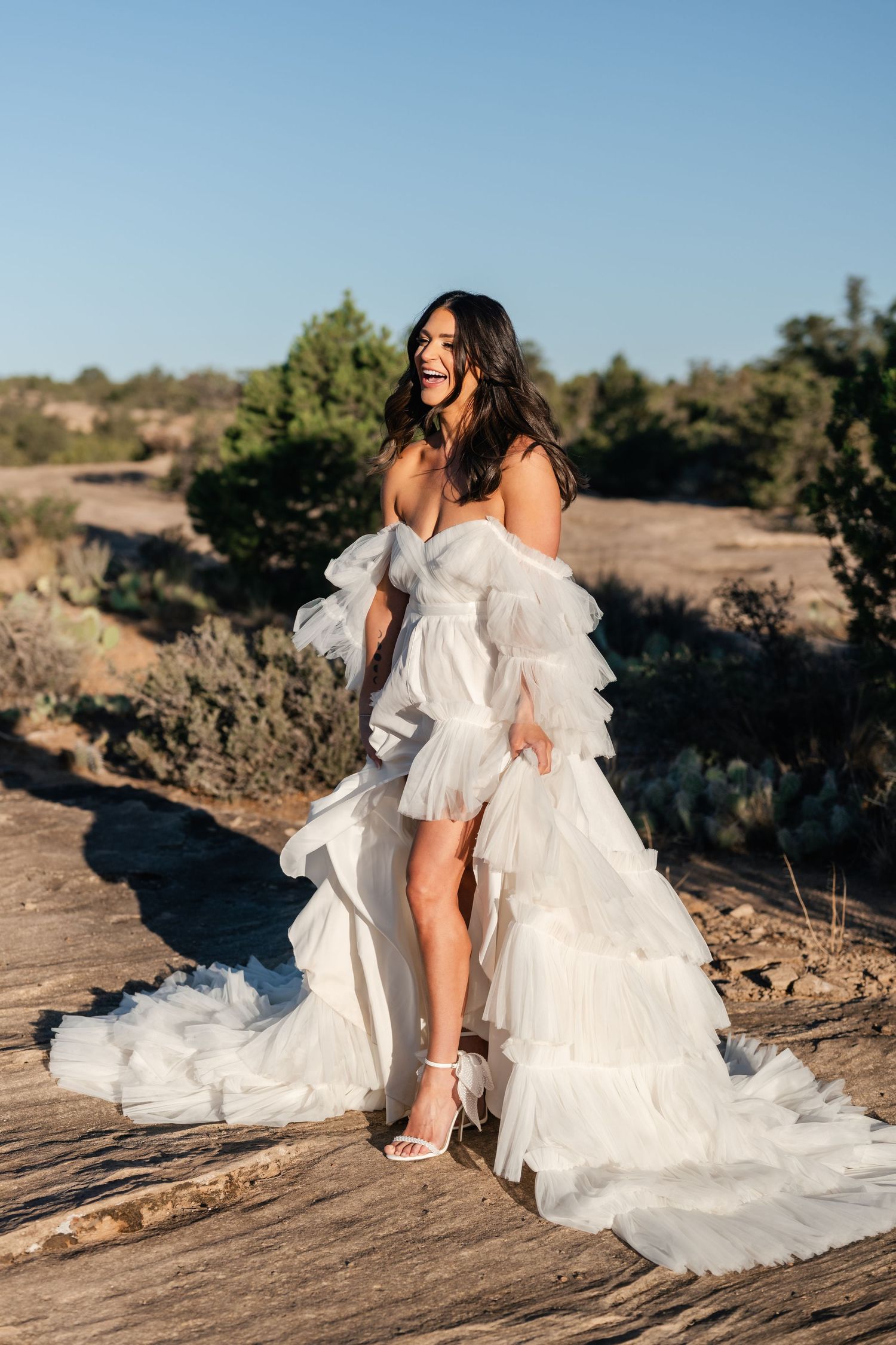 Zion Adventure Session. A flowing white dress cascades over desert rocks as sunlight illuminates the natural landscape.