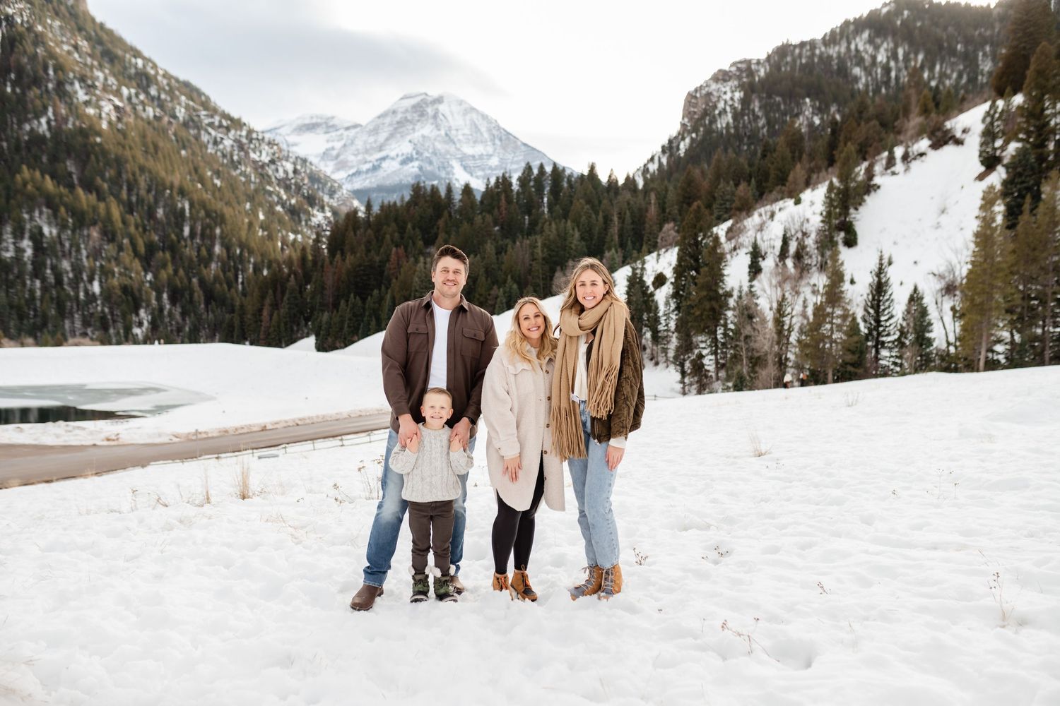 A group poses together in a snowy winter mountain landscape with snow-capped peaks in the background.