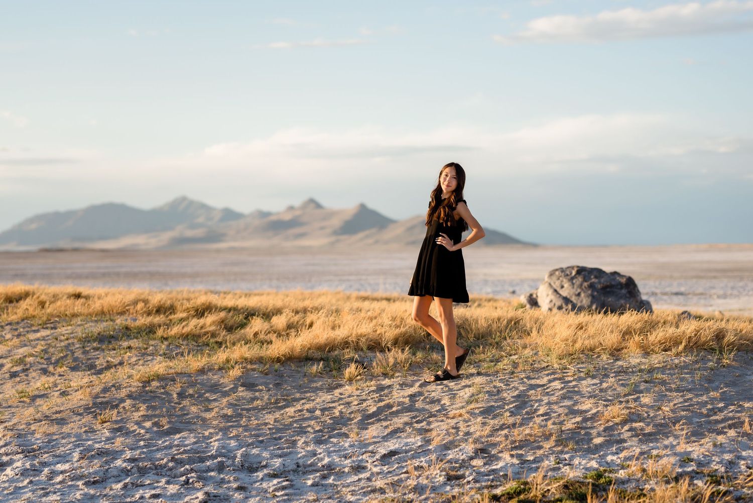 A figure stands on a hilltop at sunset, silhouetted against a dramatic mountain landscape in the background.