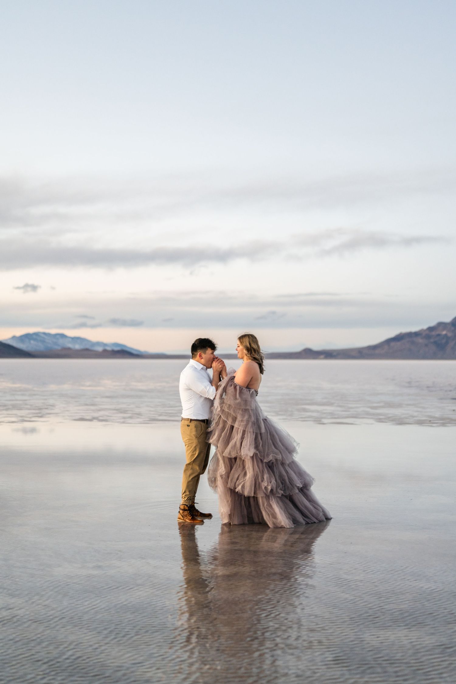 Romantic moment captured as the couple embraces amidst the serene beauty of the flooded Salt Flats during blue hour