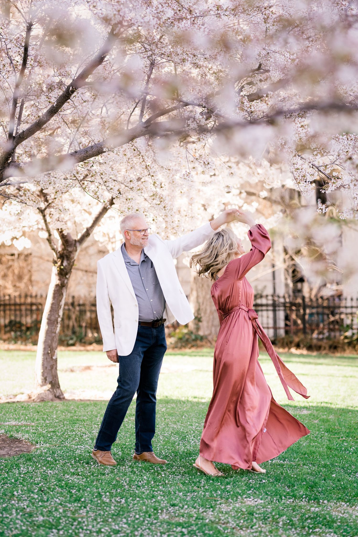 Engaged couple dance together under the blossoms at the Utah State Capitol by Utah engagement photographer Coley Cook