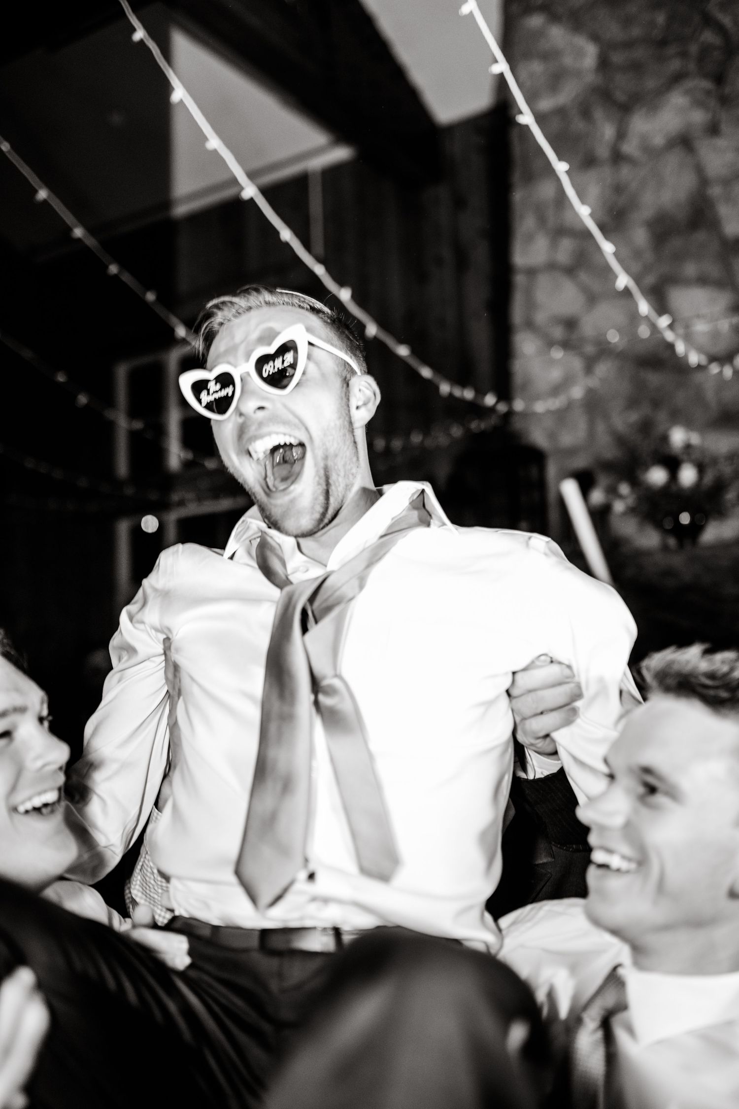 A person wearing novelty sunglasses displays exuberant joy during a wedding reception celebration. Utah Wedding Photographer.