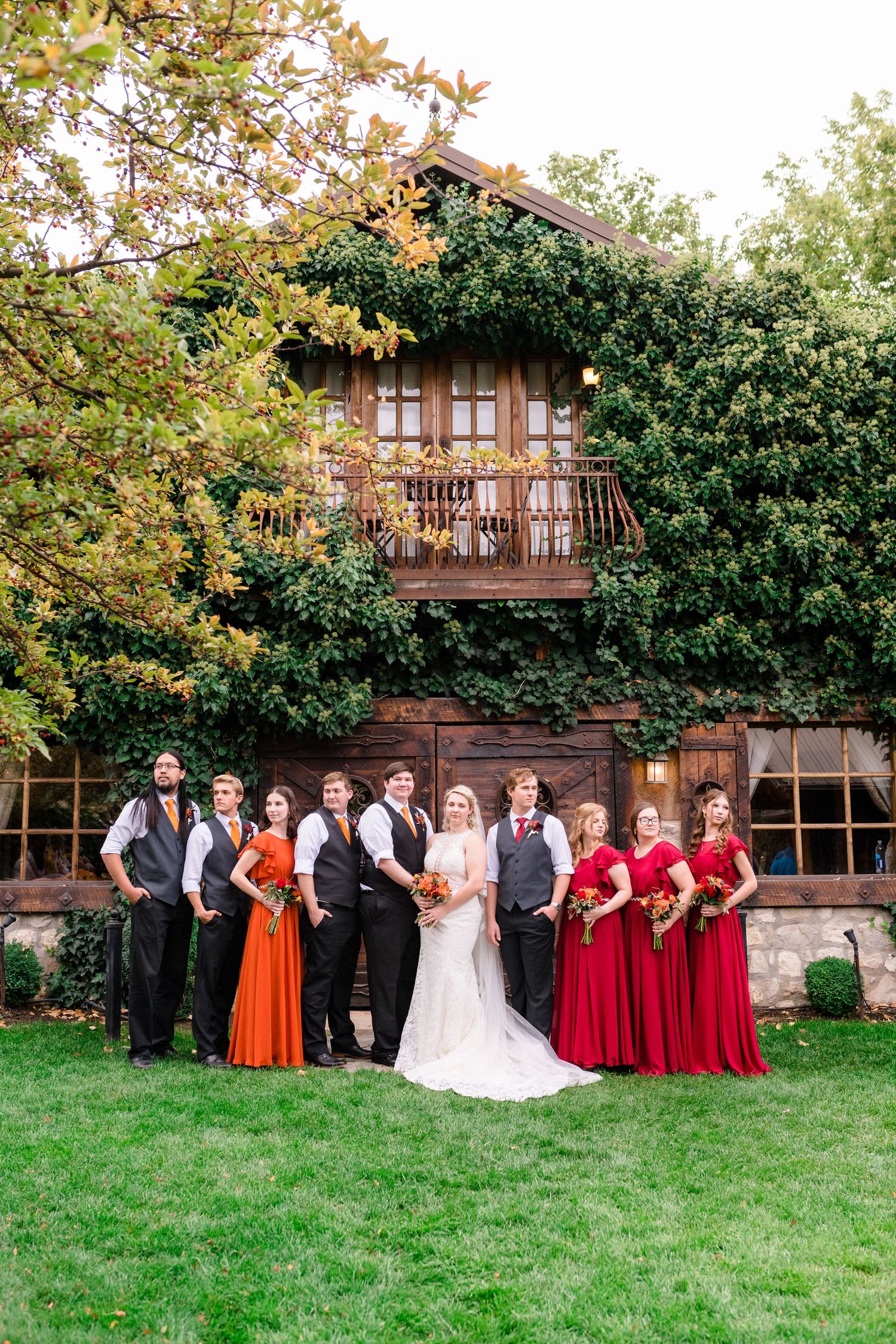 Wedding party poses on grass in front of rustic wooden lodge at Wadley Farms, a Utah County wedding venue.