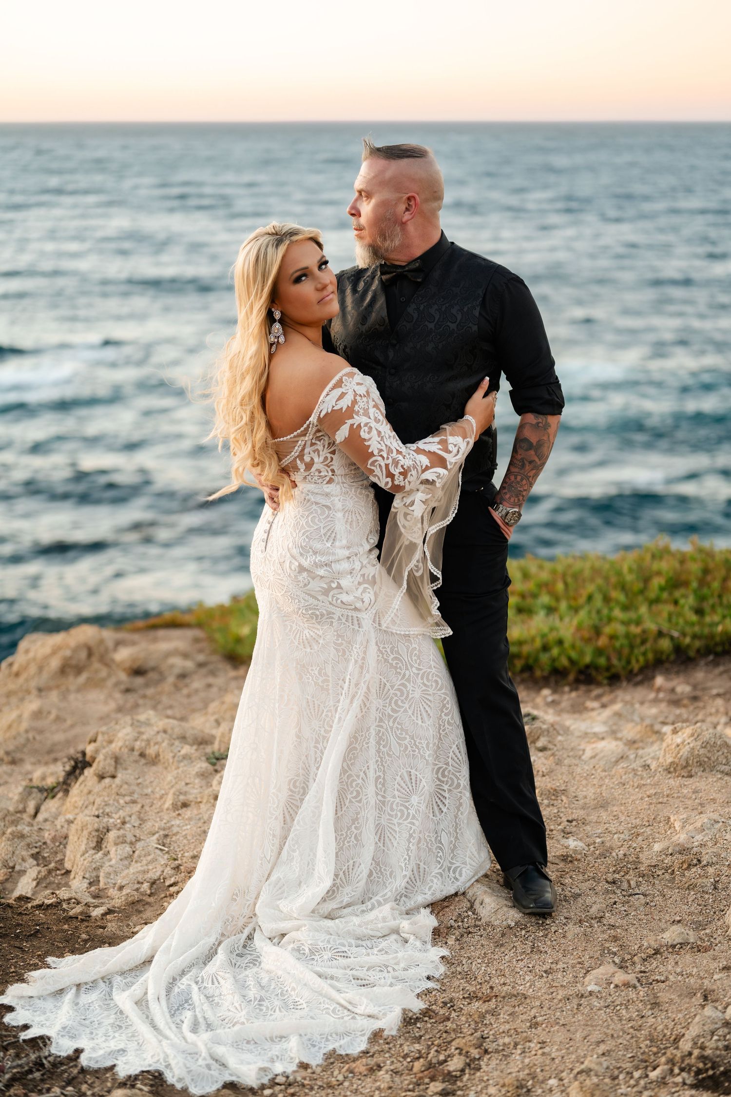 A couple shares an intimate moment during their beach wedding photoshoot at golden hour along the California coast.