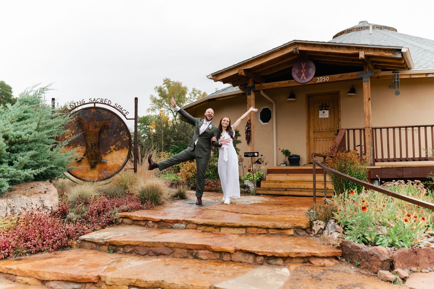 Row of adobe-style vacation cabins with wooden decks set along a winding desert path surrounded by native plants.